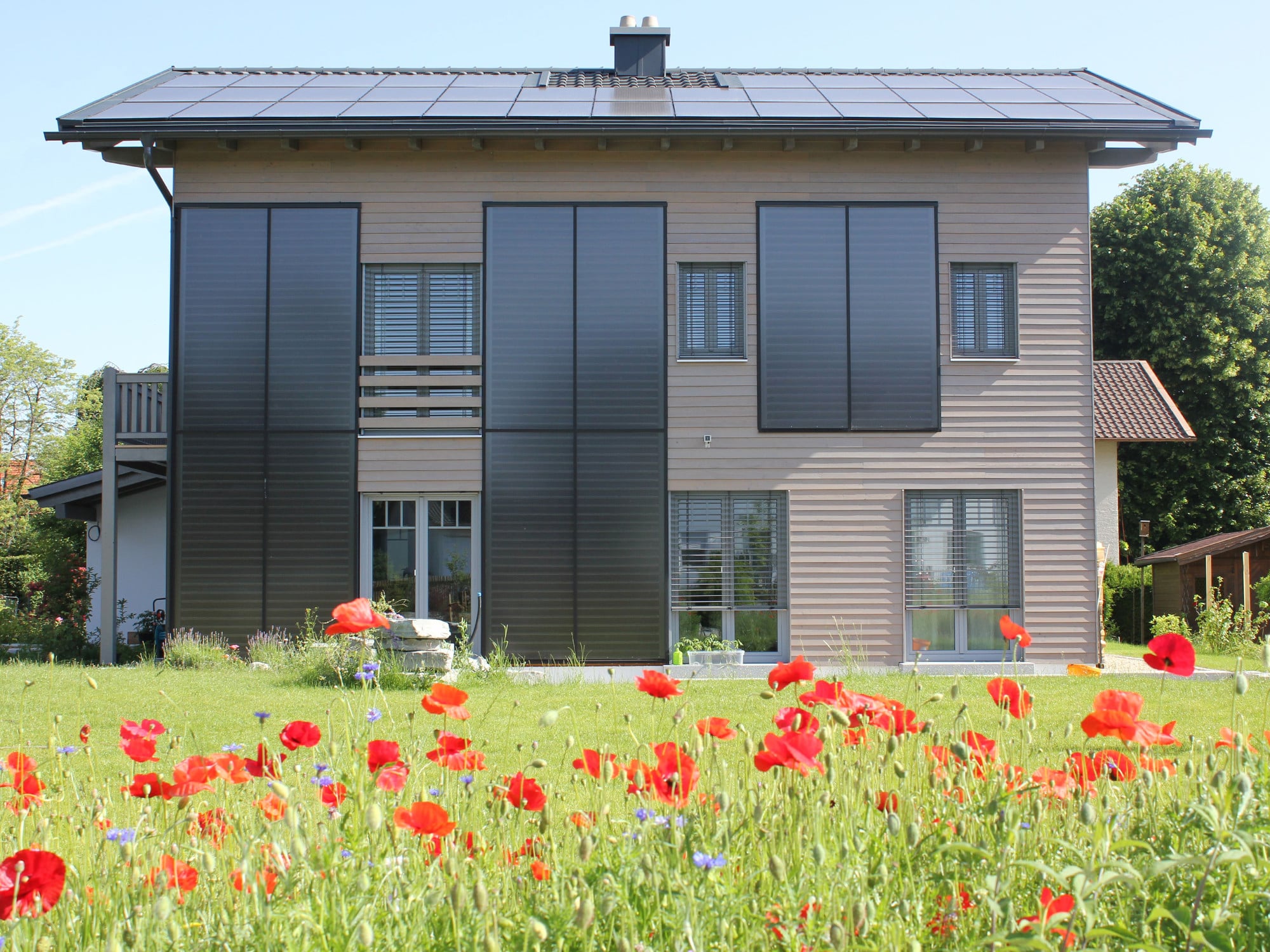 Bei dem Einfamilienhaus in Prien erzeugen große Solarthermie- und Photovoltaikanlagen an der Fassade und auf dem Dach die Energie für Wärme und Strom.