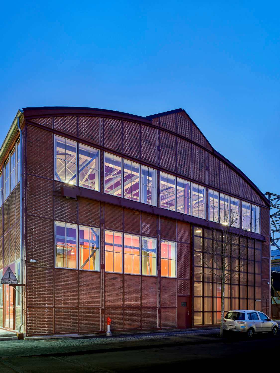 Südfassade der Montagehalle am Abend: Die Kopfbauten mit Büros und Veranstaltungsräumen sind als Haus im Haus konzipiert.