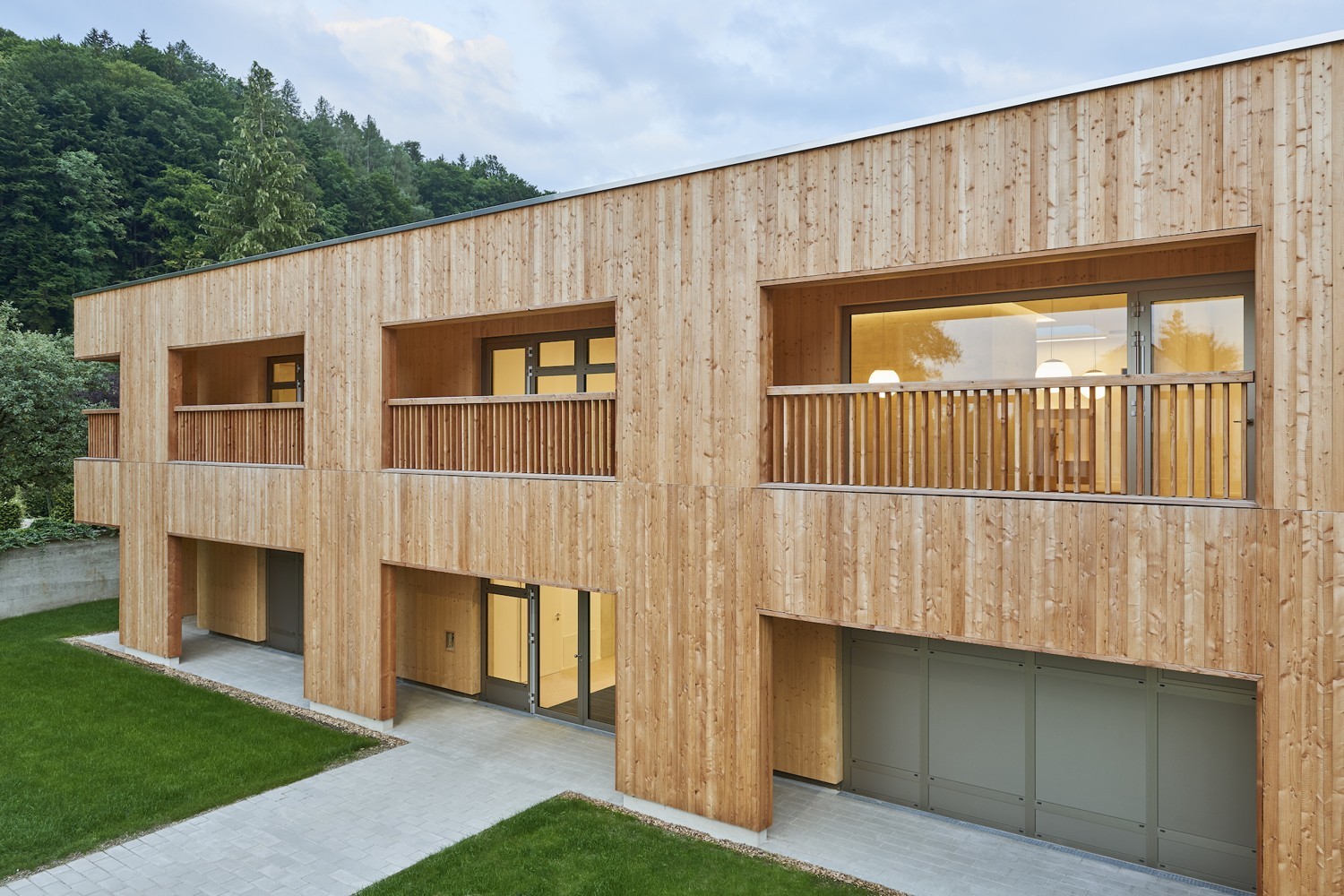 Eine naturbelassene, sägeraue Lärchenholzschalung prägt das Erscheinungsbild des zweigeschossigen Riegels, der sich damit gut in die ländliche Umgebung einfügt. 