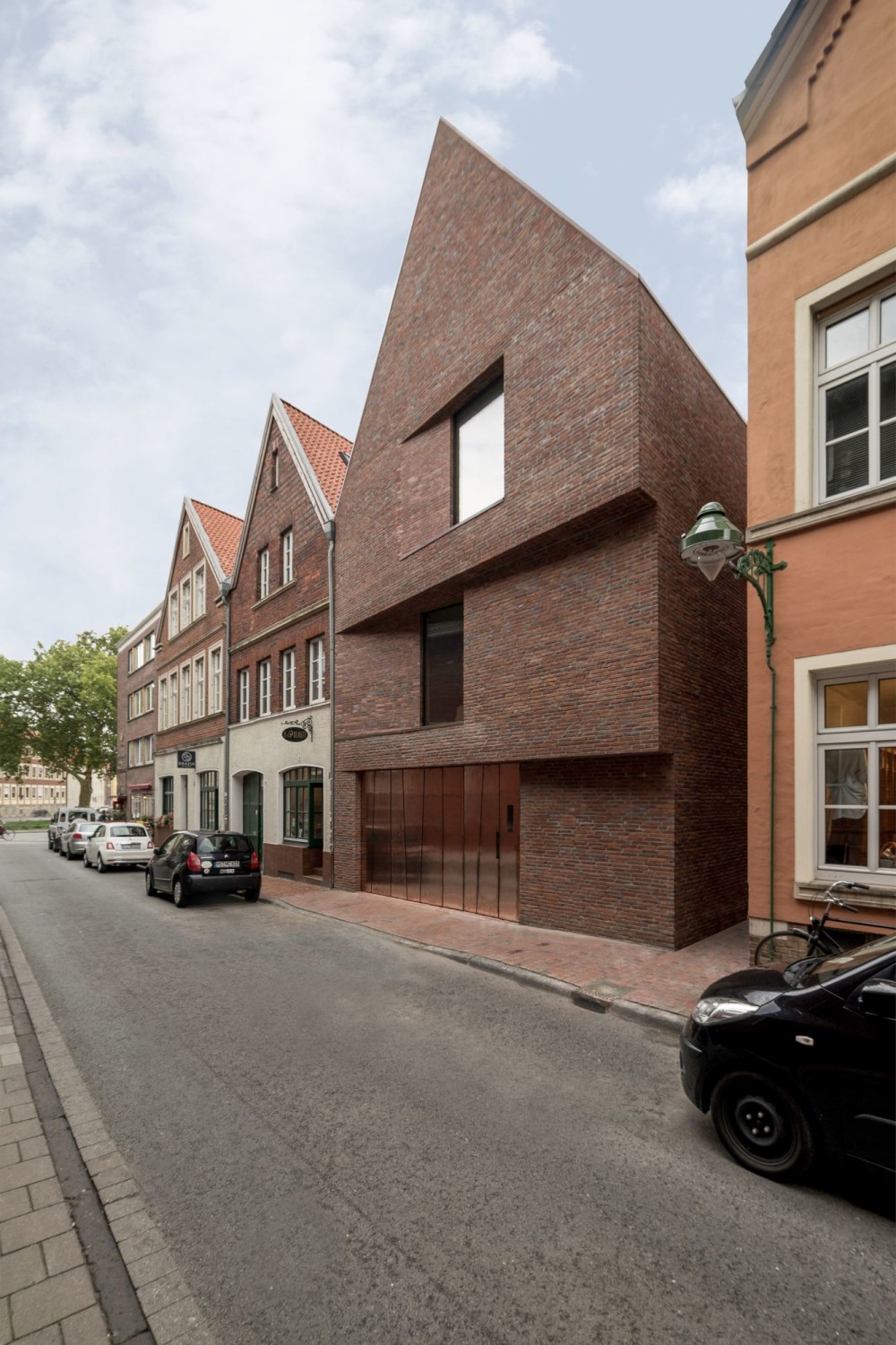 Zwei schräg verlaufende Versprünge in der ansonsten eher geschlossen wirkenden Straßenseite gliedern die Fassade.
