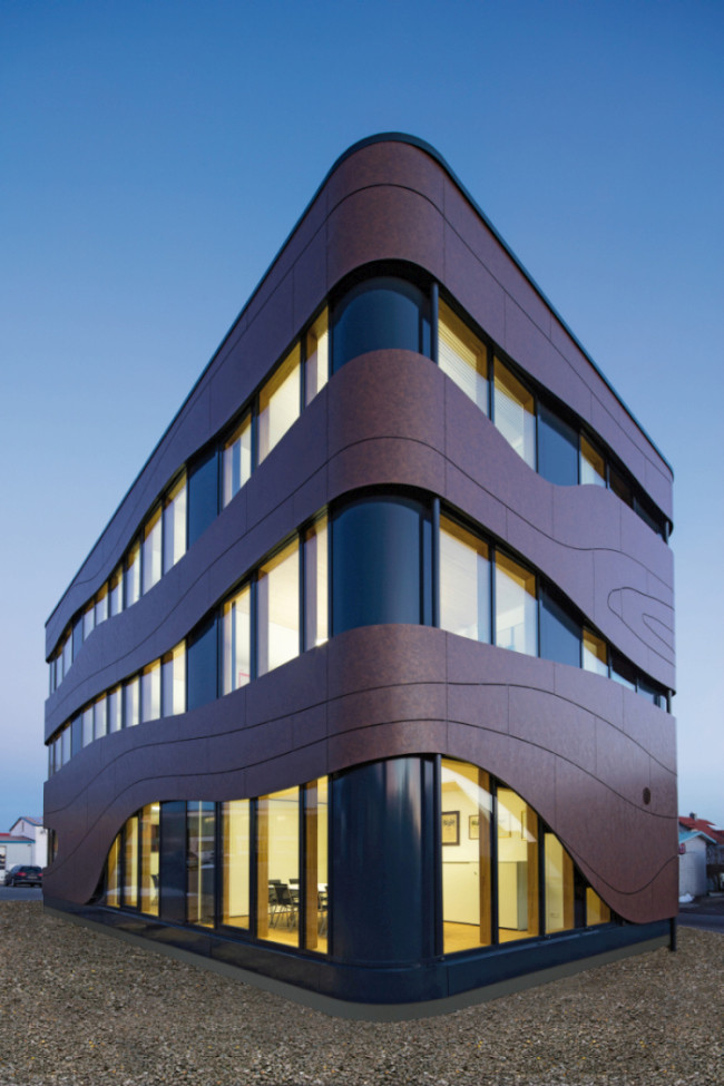 Für die Fassade wurden Holzrahmen mit einer Pfosten-Riegel-Konstruktion kombiniert, die Bekleidung besteht aus HPL- (High-Pressure-Laminat-) Platten, die Assoziationen mit einer Holzmaserung wecken. 