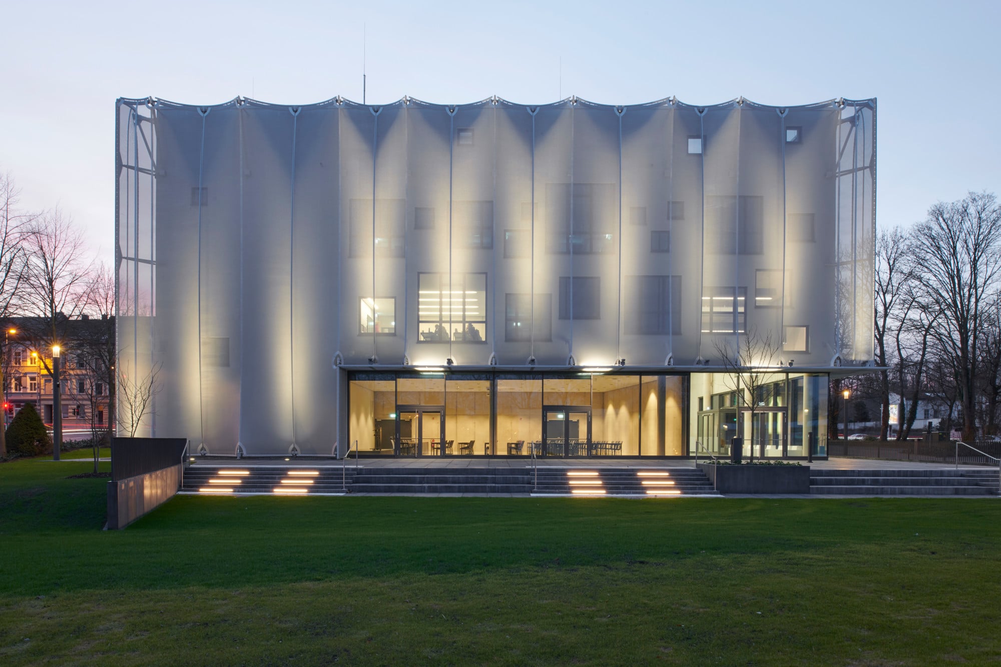 Das dreigeschossige Gebäude auf quadratischem Grundriss wird - passend zur Nutzung - von einer Textilfassade umhüllt.