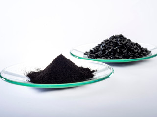 Das Schwarzpigment Bayferrox 303 T (vorn) wird zur Einfärbung von Kunststoffadditiven in Granulatform (hinten) verwendet und soll die Nah-Infrarotstrahlung (NIR) des Sonnenlichts stärker als vergleichbare Produkte reflektieren.