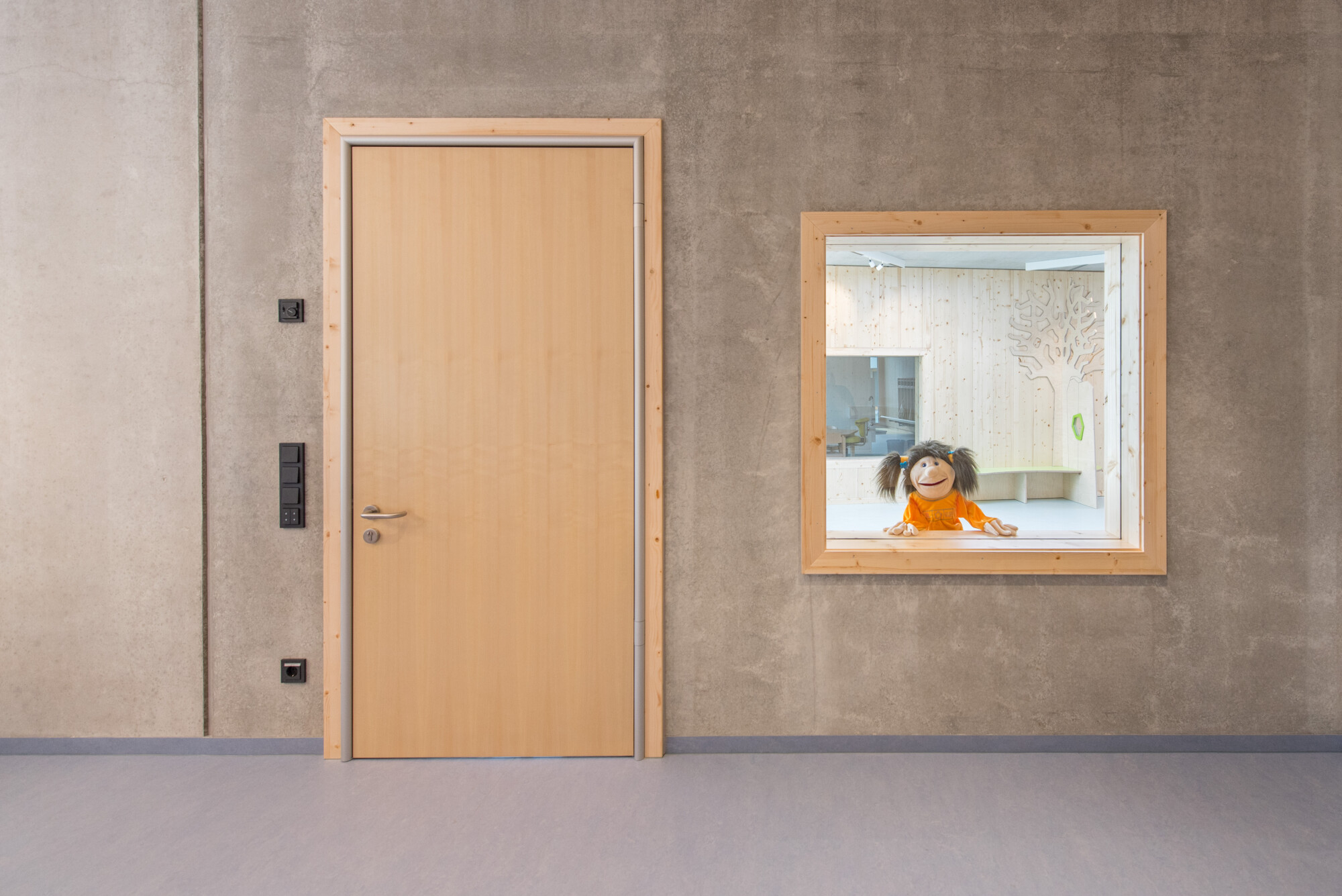 Das von Munzarchitekt entworfene Gebäude bietet Platz für zwei Regelgruppen und eine Kinderkrippe und ist geprägt durch die Materialien Sichtbeton, Fichtenholz und Glas. 