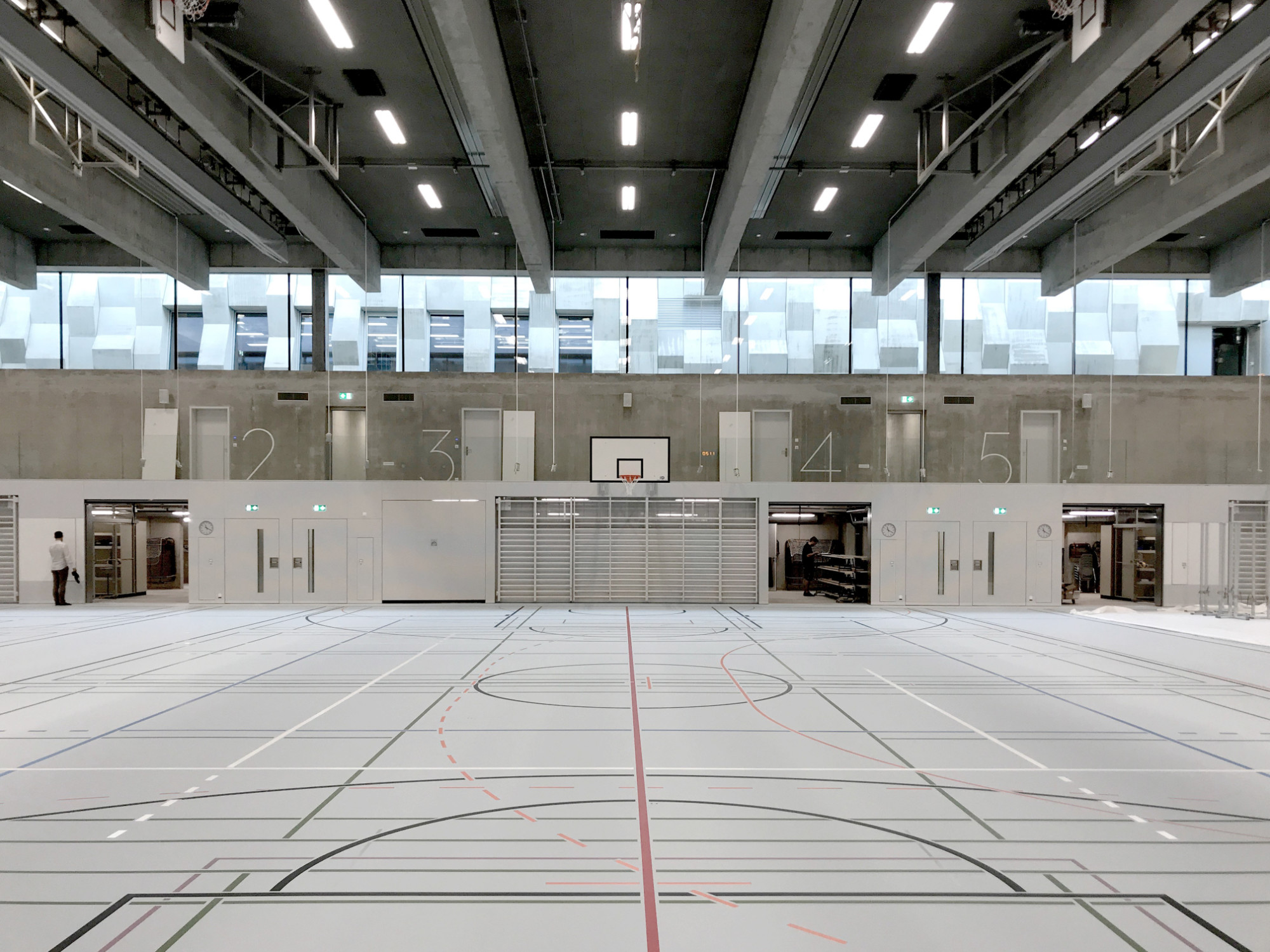 Blick aus der neuen Dreifachturnhalle auf die Promenade mit der Felswand aus Beton
