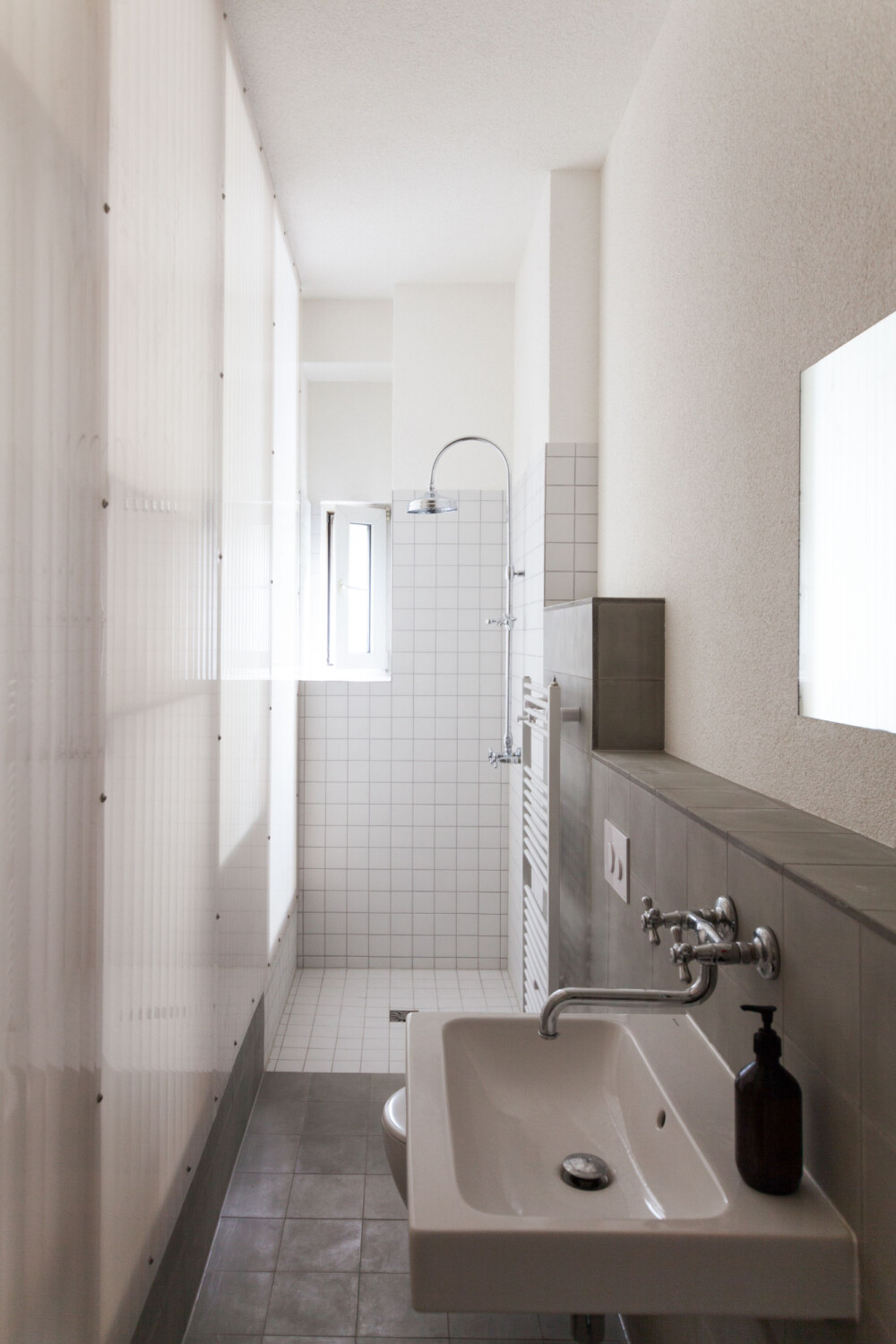 Separiert vom Wohnraum finden sich Küche und Bad, die durch eine transluzente Wand voneinander getrennt sind.