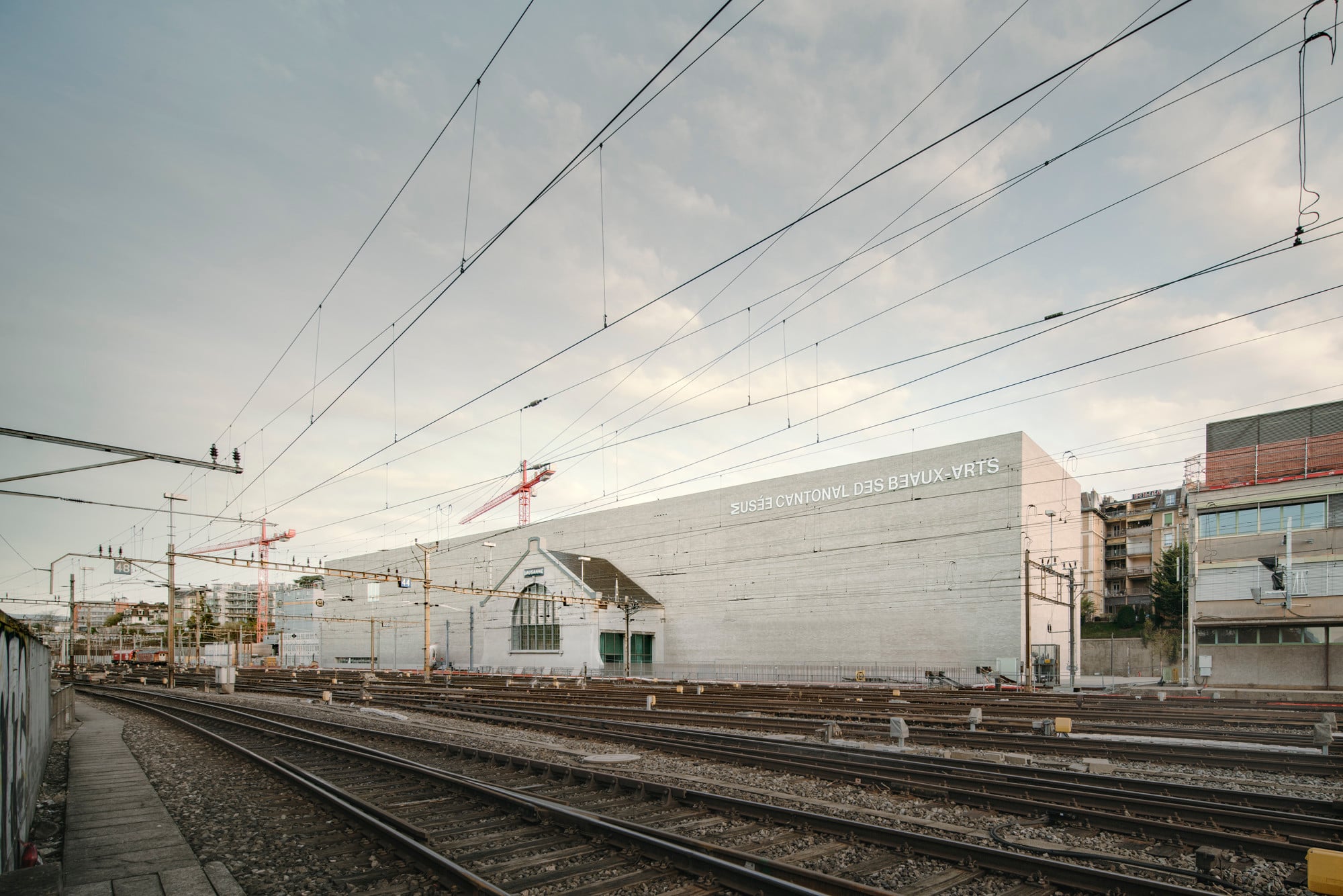 Nach Süden schirmt der Neubau das neu entstehende Quartier zu den Gleisanlagen ab. Durchbrochen wird die hier fast gänzlich geschlossene Fassade durch die bauliche Einbindung eines erhaltenen Bauteil der vormaligen Zughalle. 