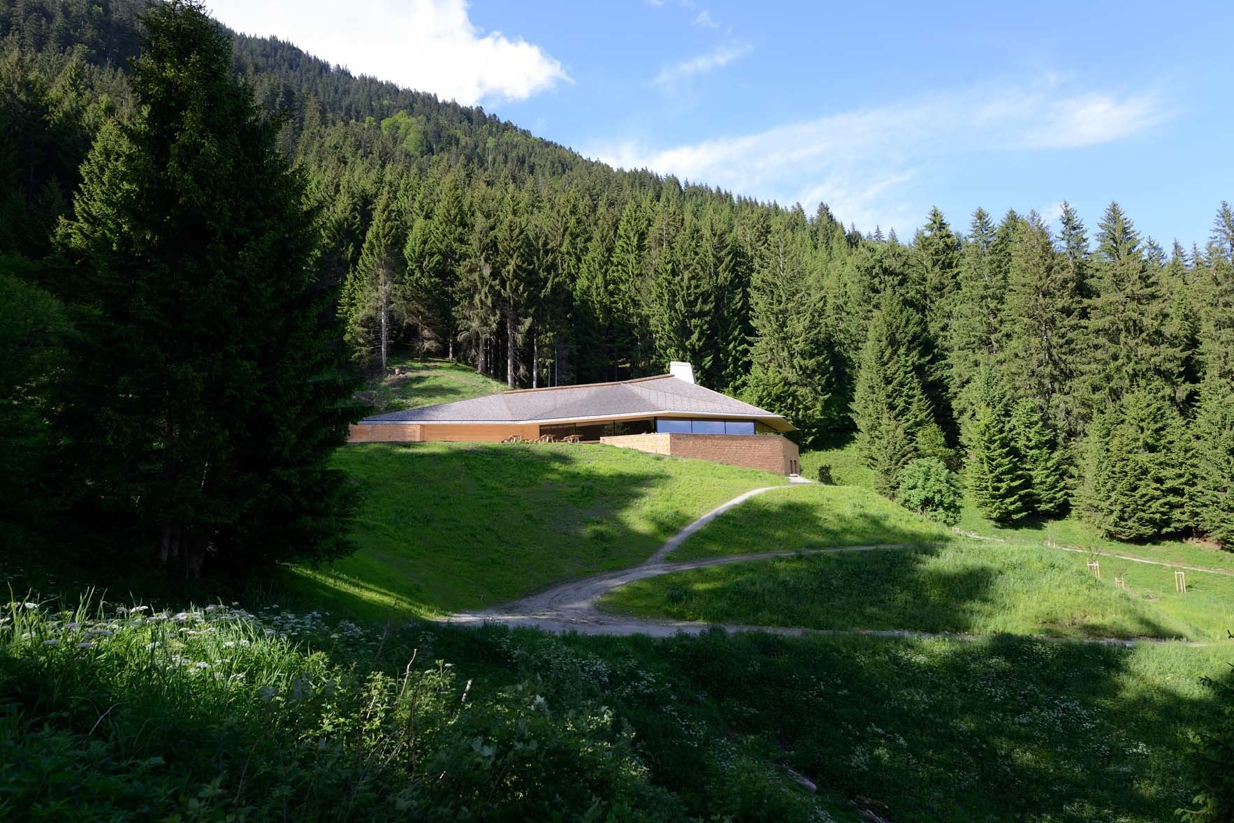 Auf einer Lichtung inmitten von hohen Bergfichten schmiegt sich das Ausflugslokal in den Hang des Karwandelgebirges.