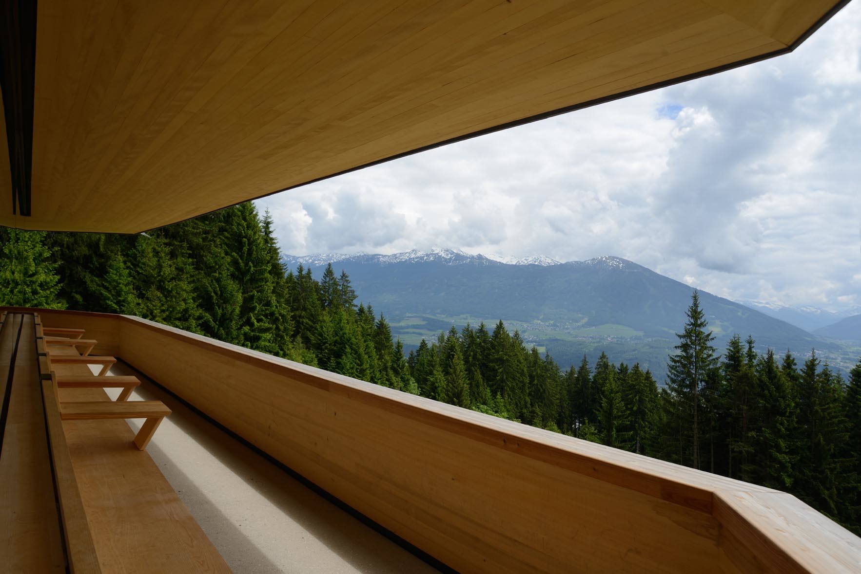 Das auskragende Dach beschirmt einen schmalen Balkon, der sich an der Südseite der Almhütte entlangwindet.