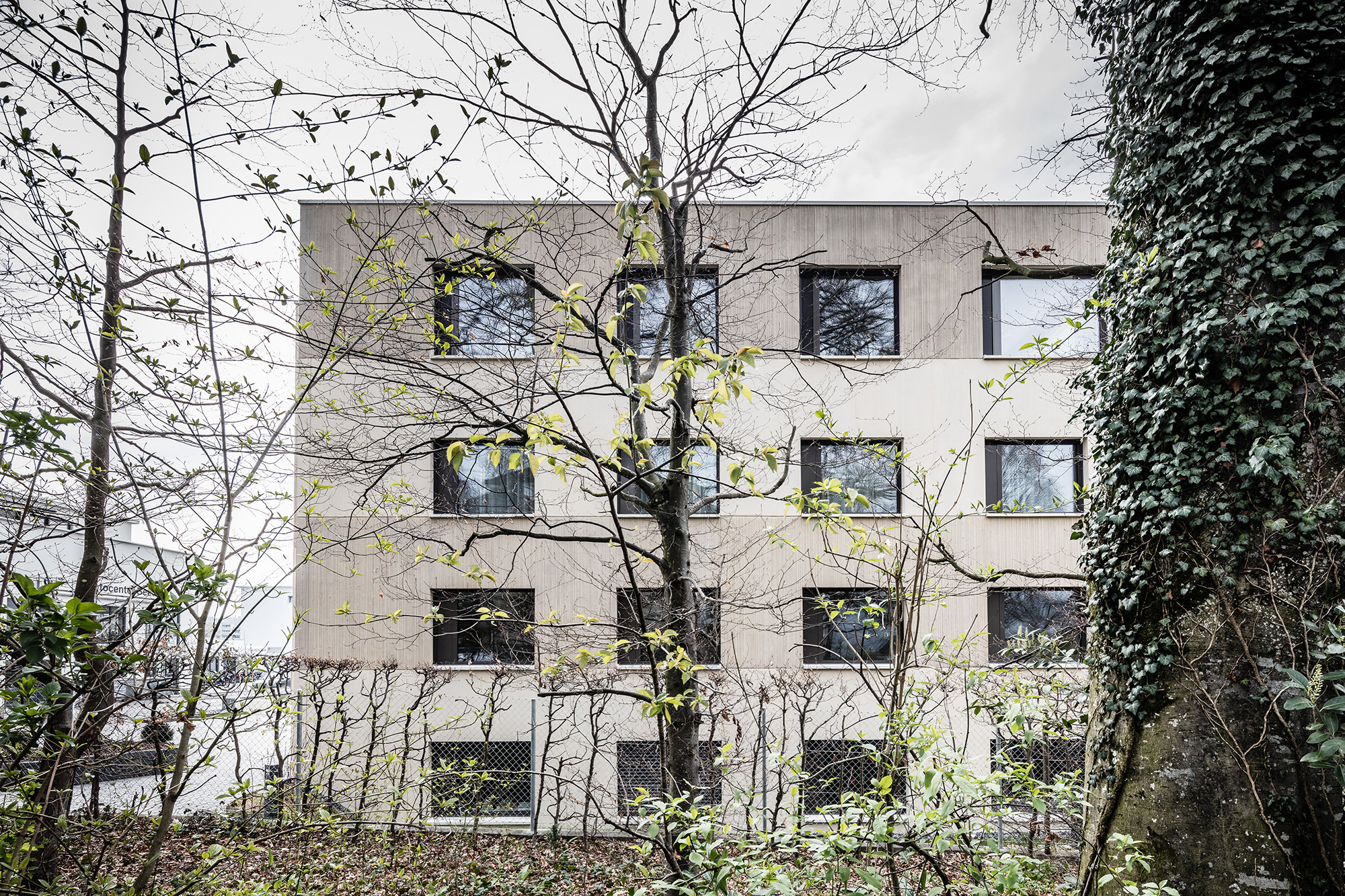 An den Gebäudeseiten zeigt die Fassade eine regelmäßige Lochfassade mit liegenden und annähernd quadratischen Öffnungen.