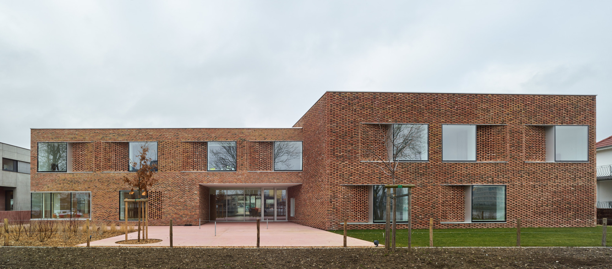 Der zweigeschossige Neubau bietet Platz für 24 Bewohner und ein vielfältiges Raumprogramm, bei dem Gemeinschaftsflächen und helle Innenräume in warmen Farbtönen besonders wichtig sind (Ansicht vom Ufer).
