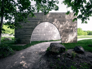 Zwei Sichtbetonscheiben formen ein Portal, das einen Zugang zum Park Chauveau in Quebec inszeniert.