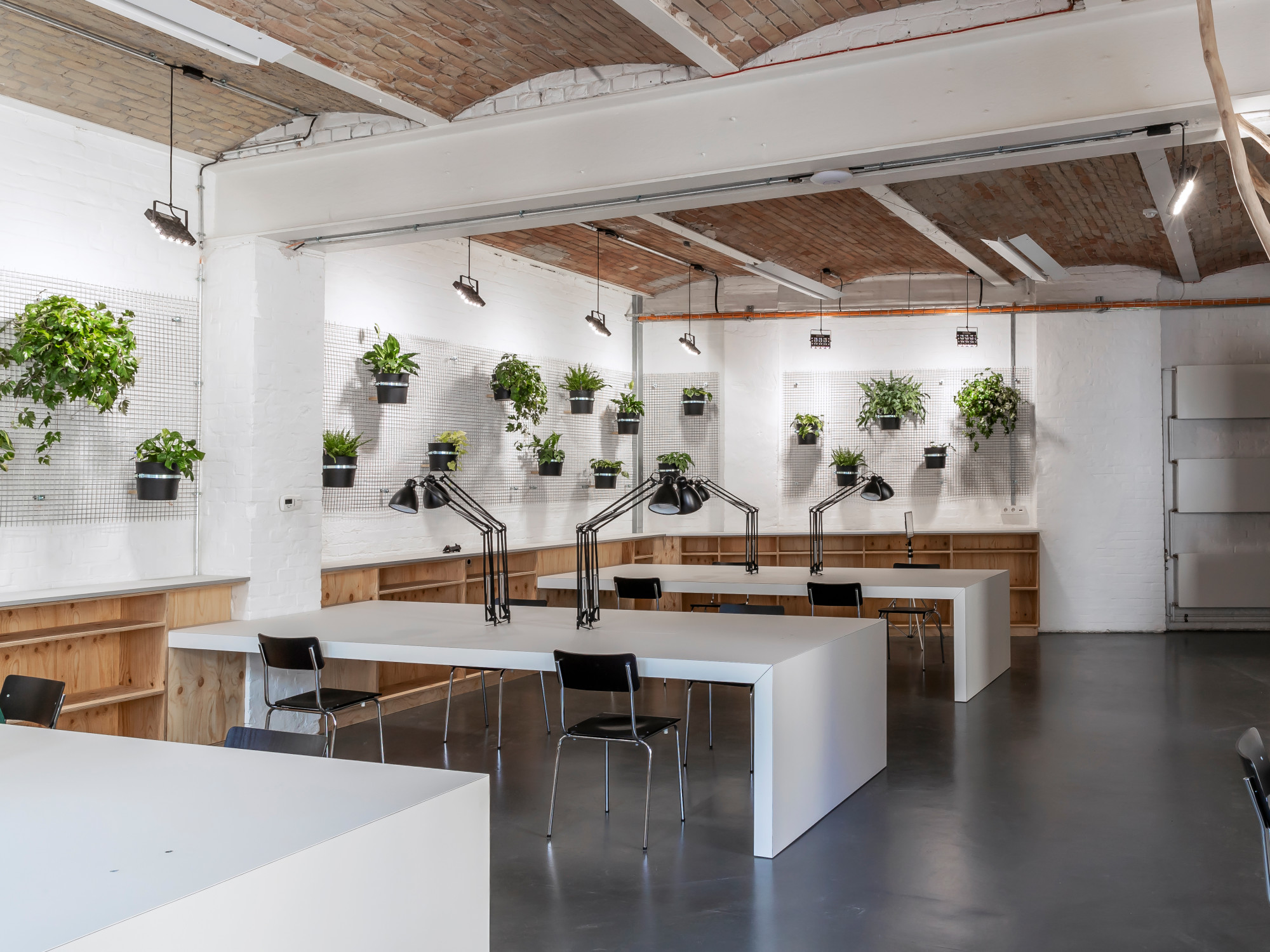 In einem Berliner Geminschavftsbüro installierten Raumstar Architekten eine Gitterwand mit angehängten Pflanztöpfen.