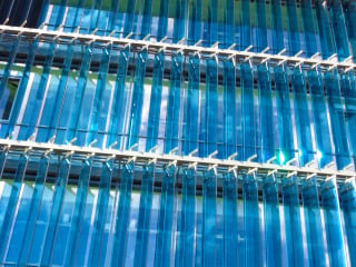 Die Anordnung der Fenster erfolgt zwar klassischerweise nach den vier Himmelrichtungen, aber in einem präziseren Sinne nach der Ekliptik der Sonne (im Bild: Fensterwand mit beweglichen Glaslamellen als Sonnen- und Blendschutz).