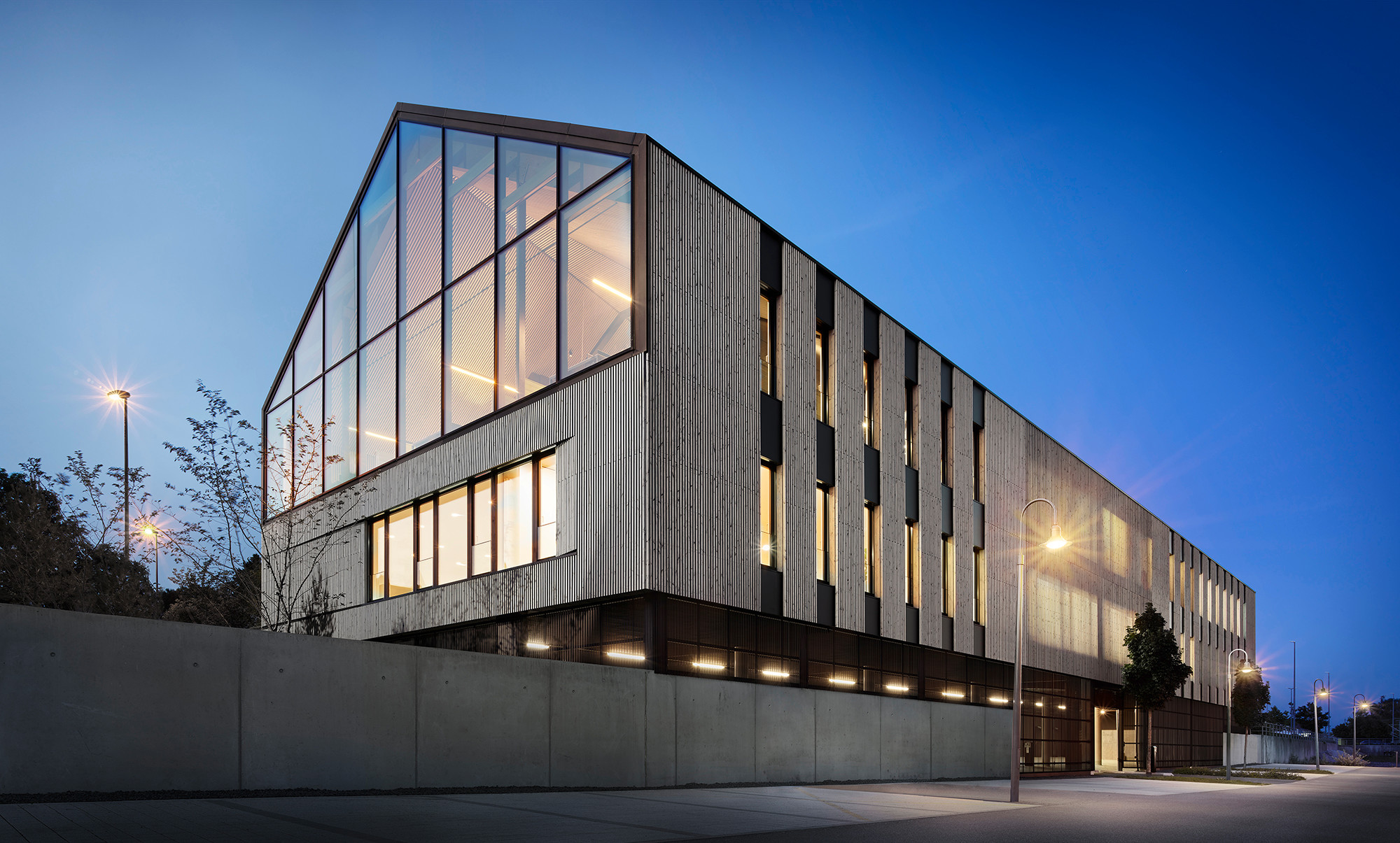 Der Geländeverlauf bildet auf dem Grundstück einen Höhenversatz von mehreren Metern, wodurch die Tiefgarage im Untergeschoss nur stadtseitig sichtbar ist – in Richtung Wohngebiet wirkt das Gebäude nur zweigeschossig. 