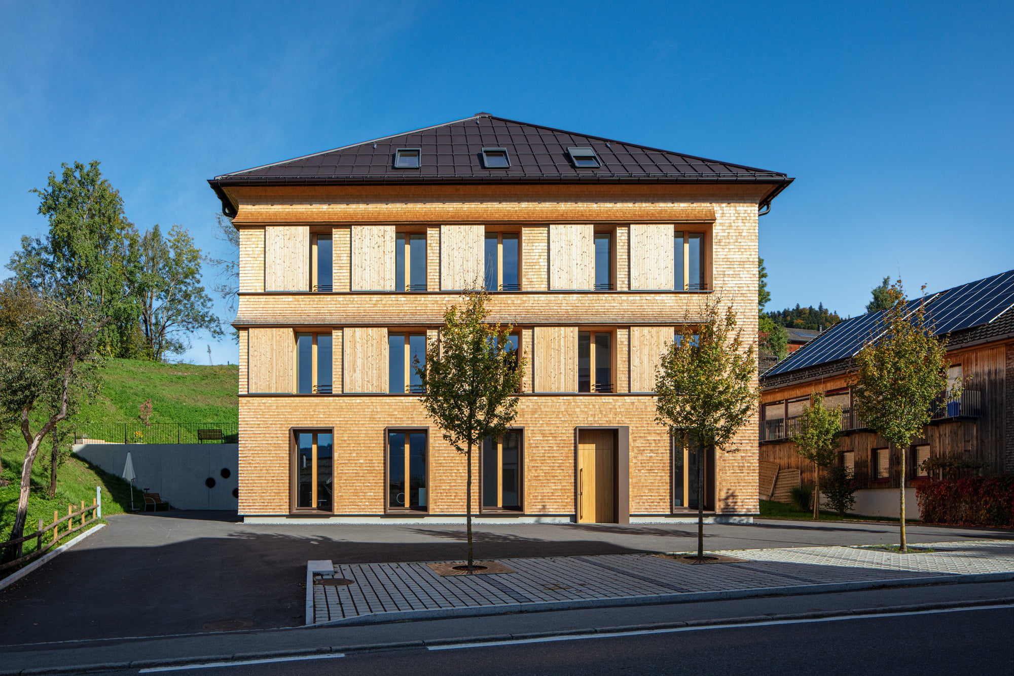 Ausschwingende Gesimse und schiebbare Fensterläden betonen die Horizontale in der Fassade.