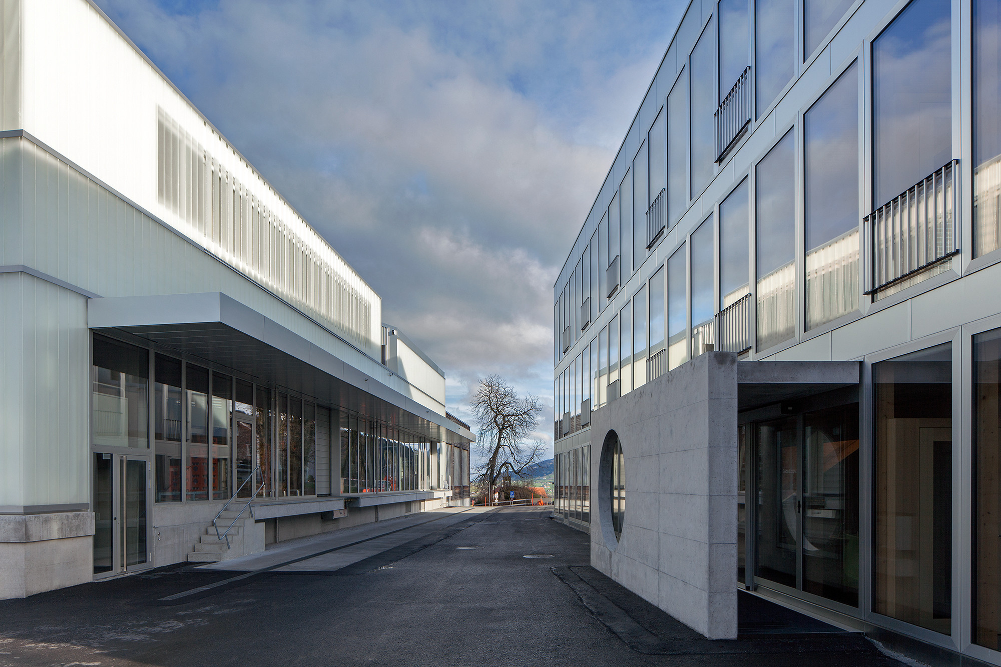 Die Transparenz des Neubaus kontrastiert mit der opaken Fassade der adaptierten Produktionsstätte.