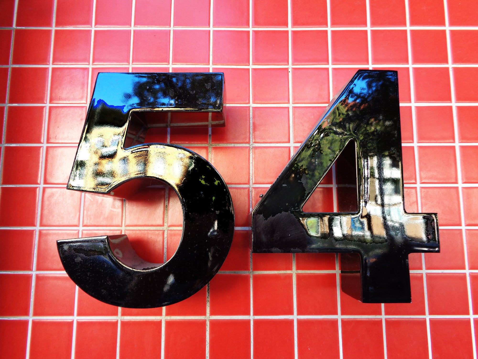 Die kommunalen Verwaltungen entscheiden über den Straßennamen und vergeben die Hausnummern, um so öffentliche Sicherheit, Ordnung und Auffindbarkeit zu gewährleisten (im Bild: historisches Emailleschild an einem Eingangstor).