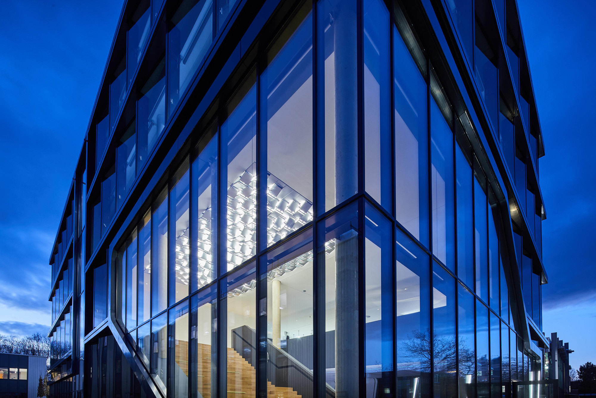 Der Haupteingang wird durch ein über Eck verlaufendes Schaufenster markiert, das im Gegensatz zum Rest der Fassade mit planaren Verglasungen ausgeführt wurde. 