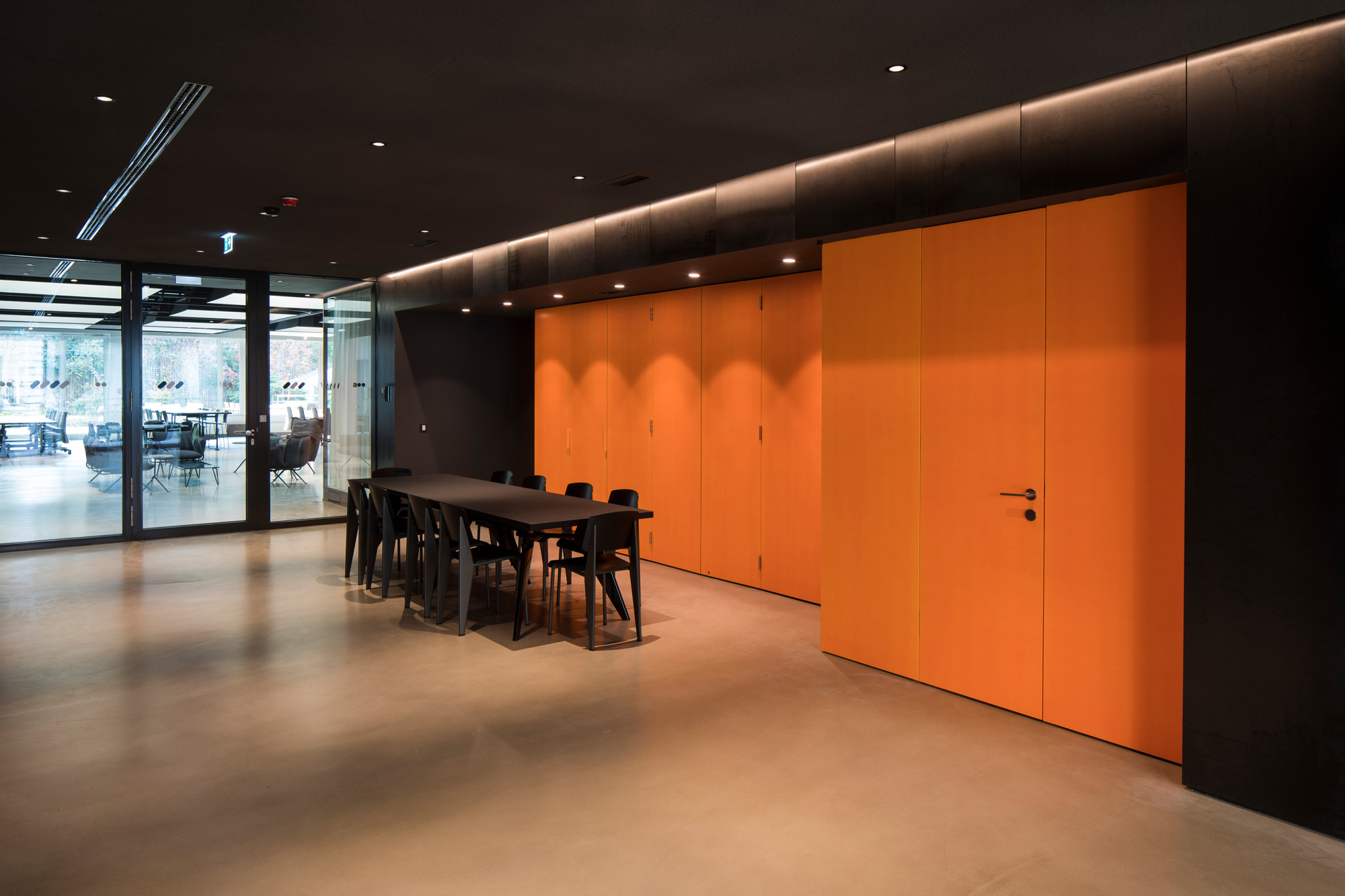 Hinter einer Wandverkleidung in leuchtendem Orange verbirgt sich eine Küchenzeile, die bei Bedarf freigelegt werden kann. 