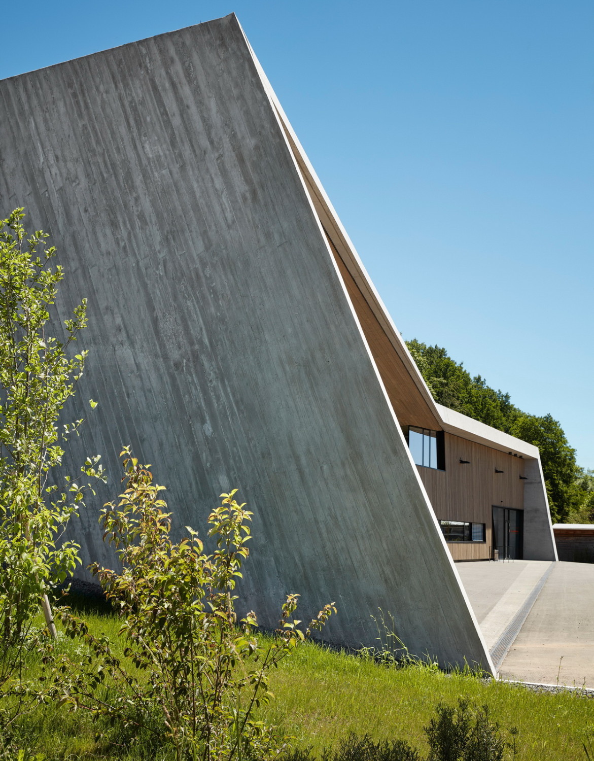 Die Oberfläche der Nordfassade nimmt die leicht gekippte Ausrichtung des Gebäudeüberstands auf und setzt diese fort, indem mit einer groben Bretterschalung eine diagonale Struktur erzeugt wurde. 