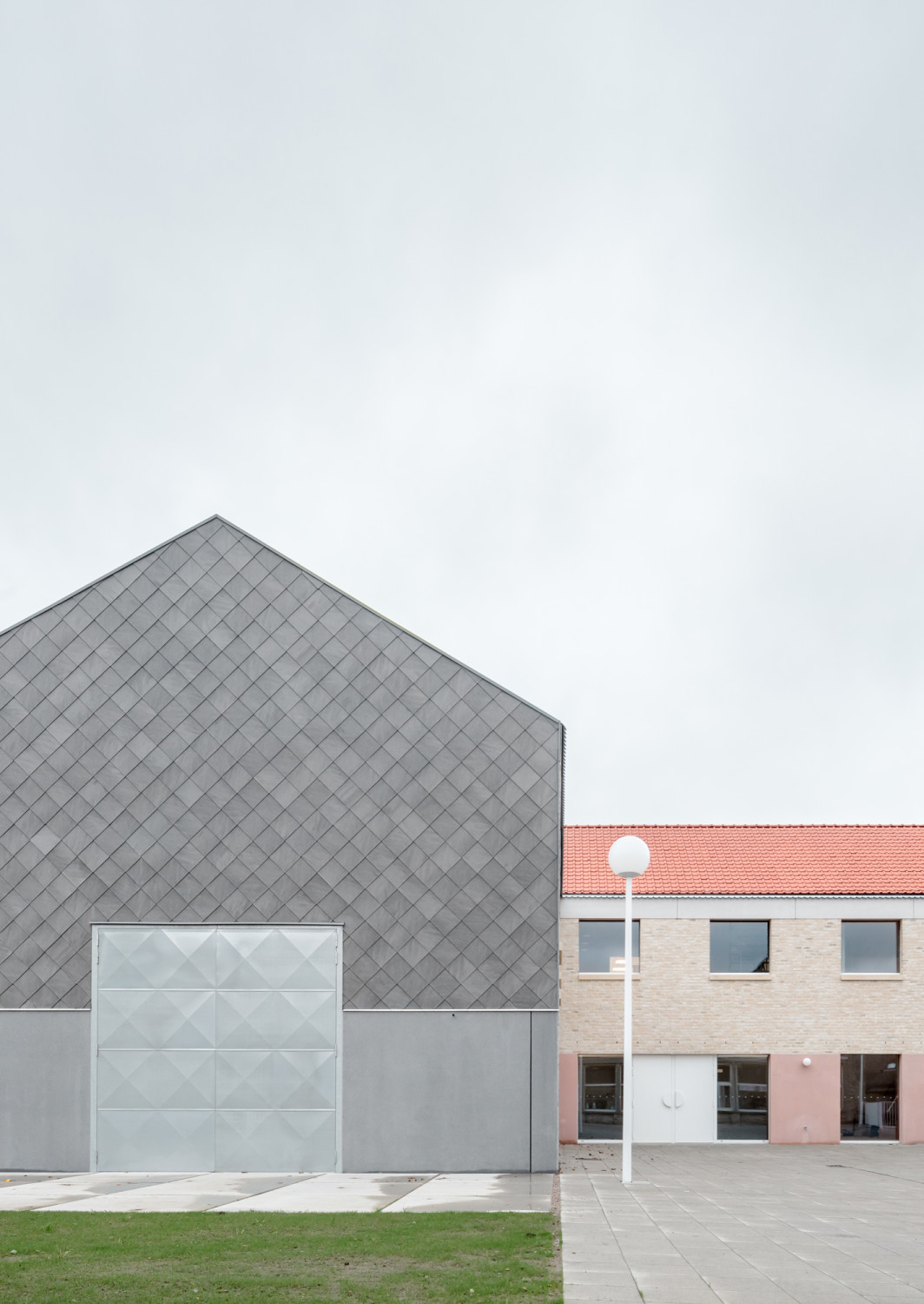 Hinter einem Altbau, der den örtlichen Kindergarten samt Vorschule beherbergt, ergänzt auf demselben Gelände ein zweiteiliger, zweigeschossiger Baukörper die Gemeentelijke Basischool De Linde. 
