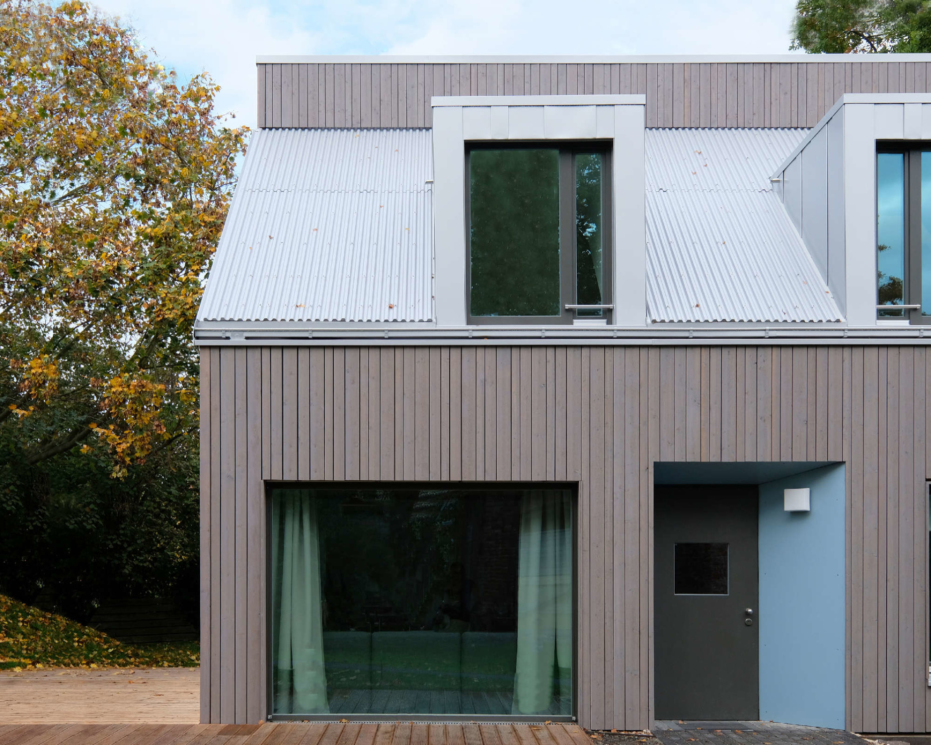 Die hell schimmernde Dachdeckung bildet einen interessanten Kontrast zur Fassade, einer umlaufend vorvergrauten Lärchenholzschalung (östliche Eingangsseite).