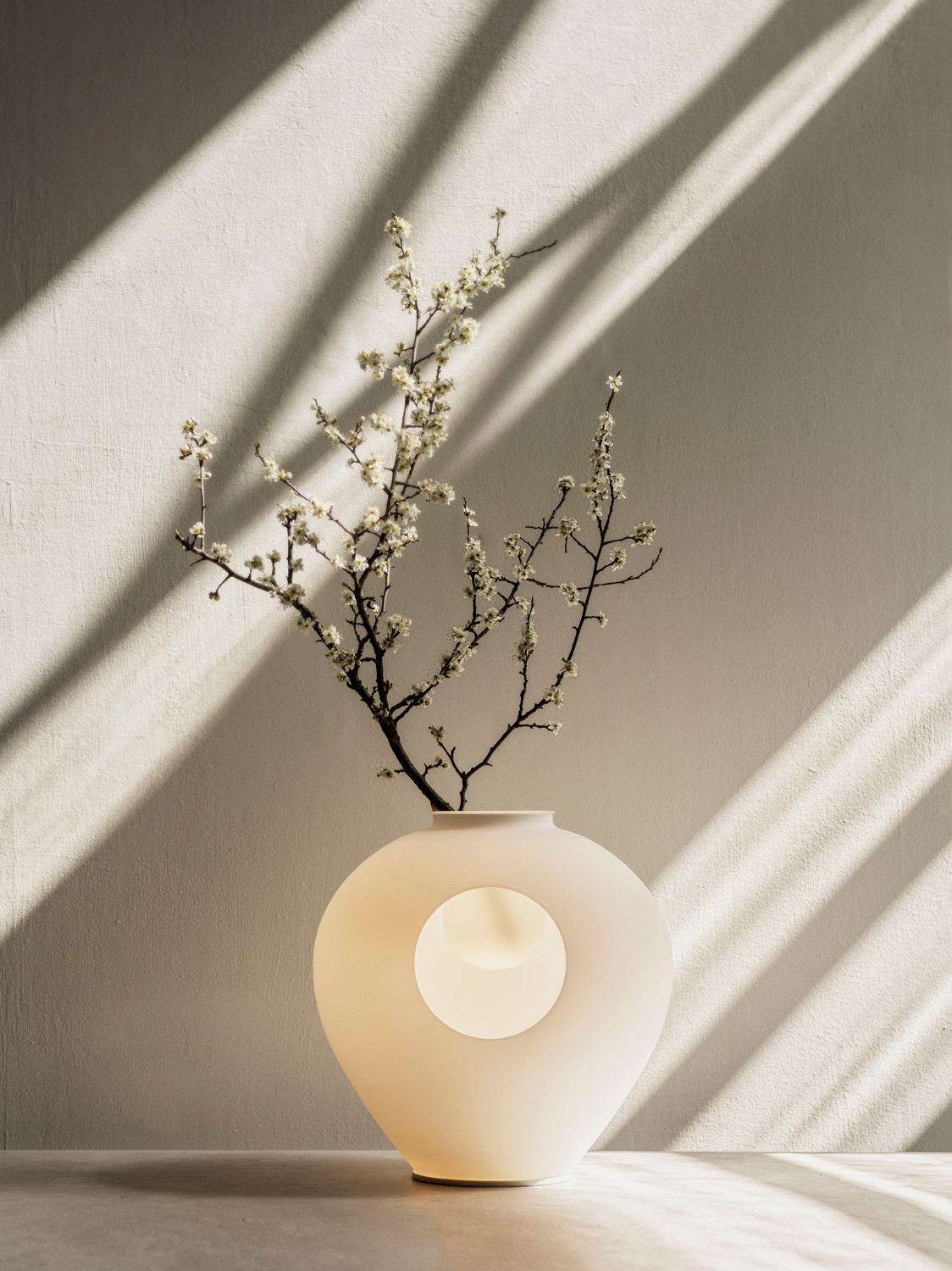 Sie ist eine Leuchte mit indirektem Ambiente-Licht, die gleichzeitig als Vase für Zweige und Blüten dienen kann.