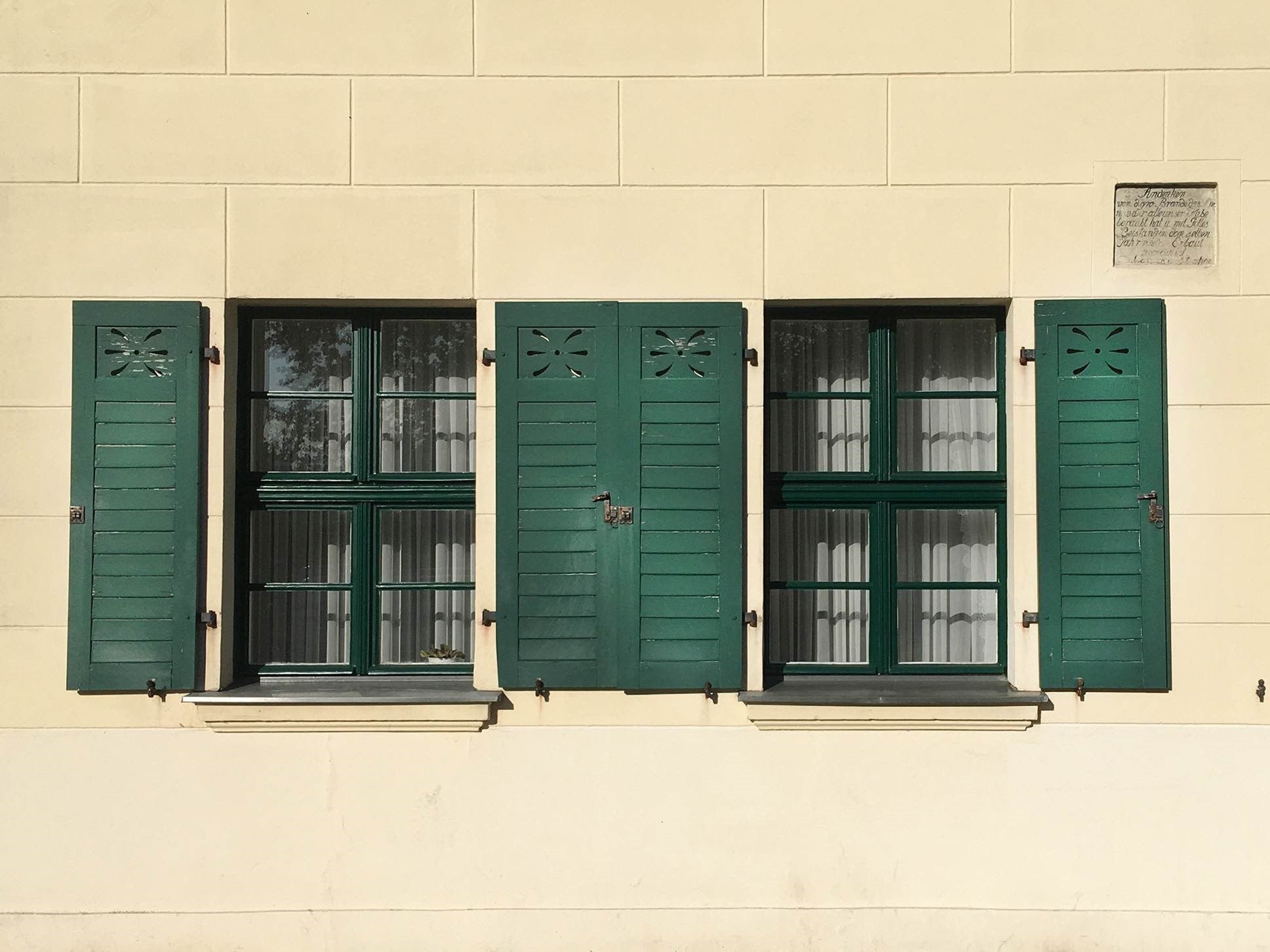 Klassische hölzerne Klappläden in Kontrastfarben lackiert an einem Sprossenfenster