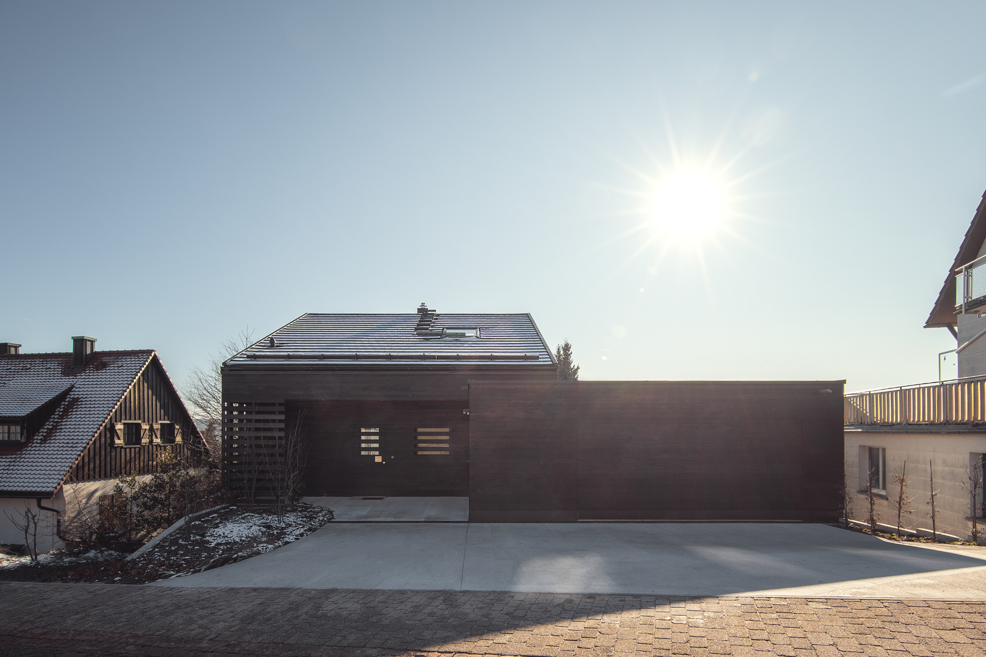 Von den anderen Bauten in der Straße unterscheidet das von Partner und Partner Architekten geplante Einfamilienhaus allein durch seine schwarze Fassade aus gebranntem Holz. 