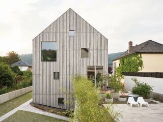 Mit seiner schlichten, archetypischen Form, betont durch ein minimal überstehendes Satteldach, fügt sich das Wohnhaus gut in die Nachbarschaft. 