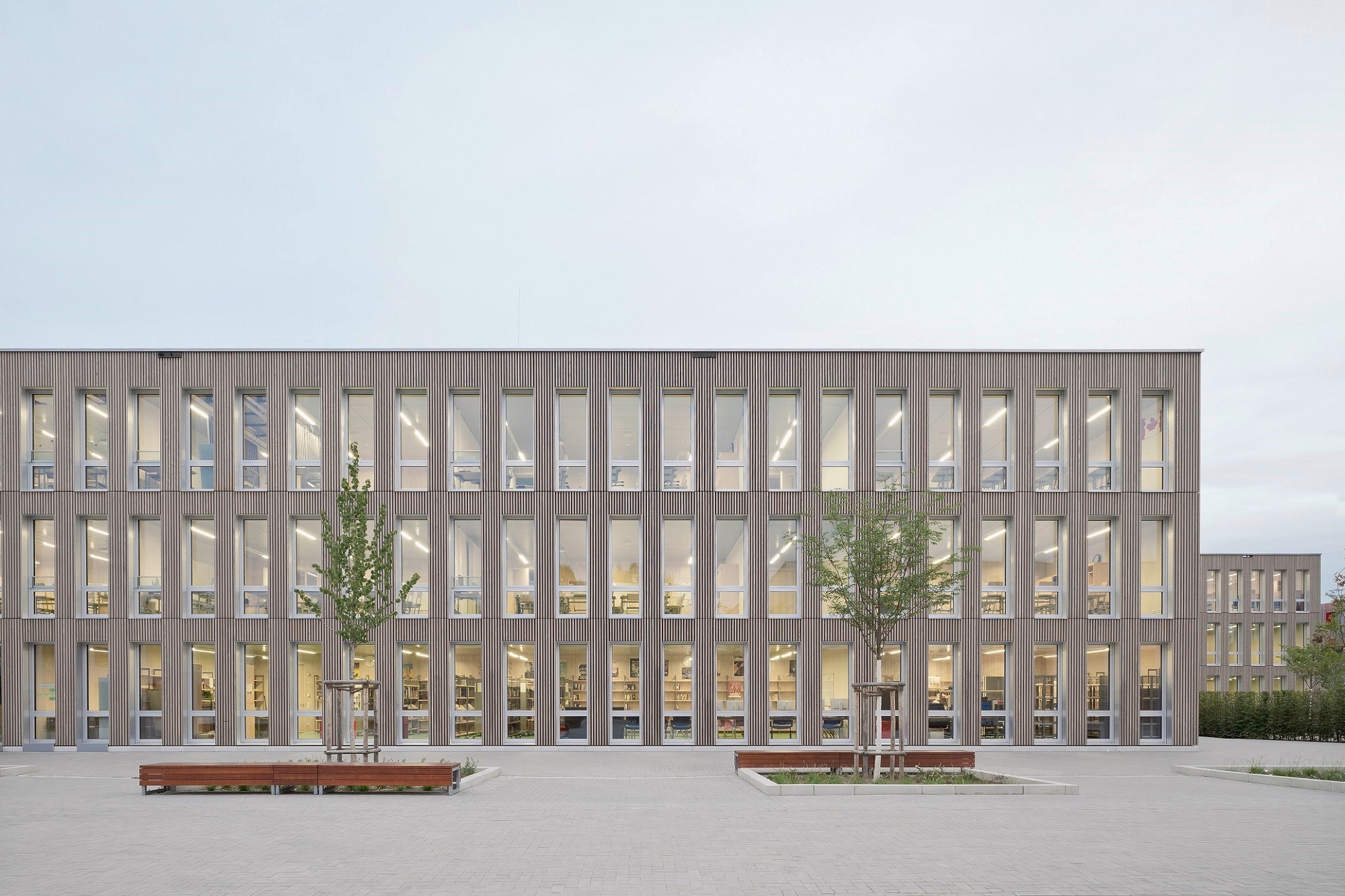 Die Fassade aus vorvergrauten Weißtannenholzleisten ist gegliedert durch schmale, rhythmisch angeordnete Fenster.