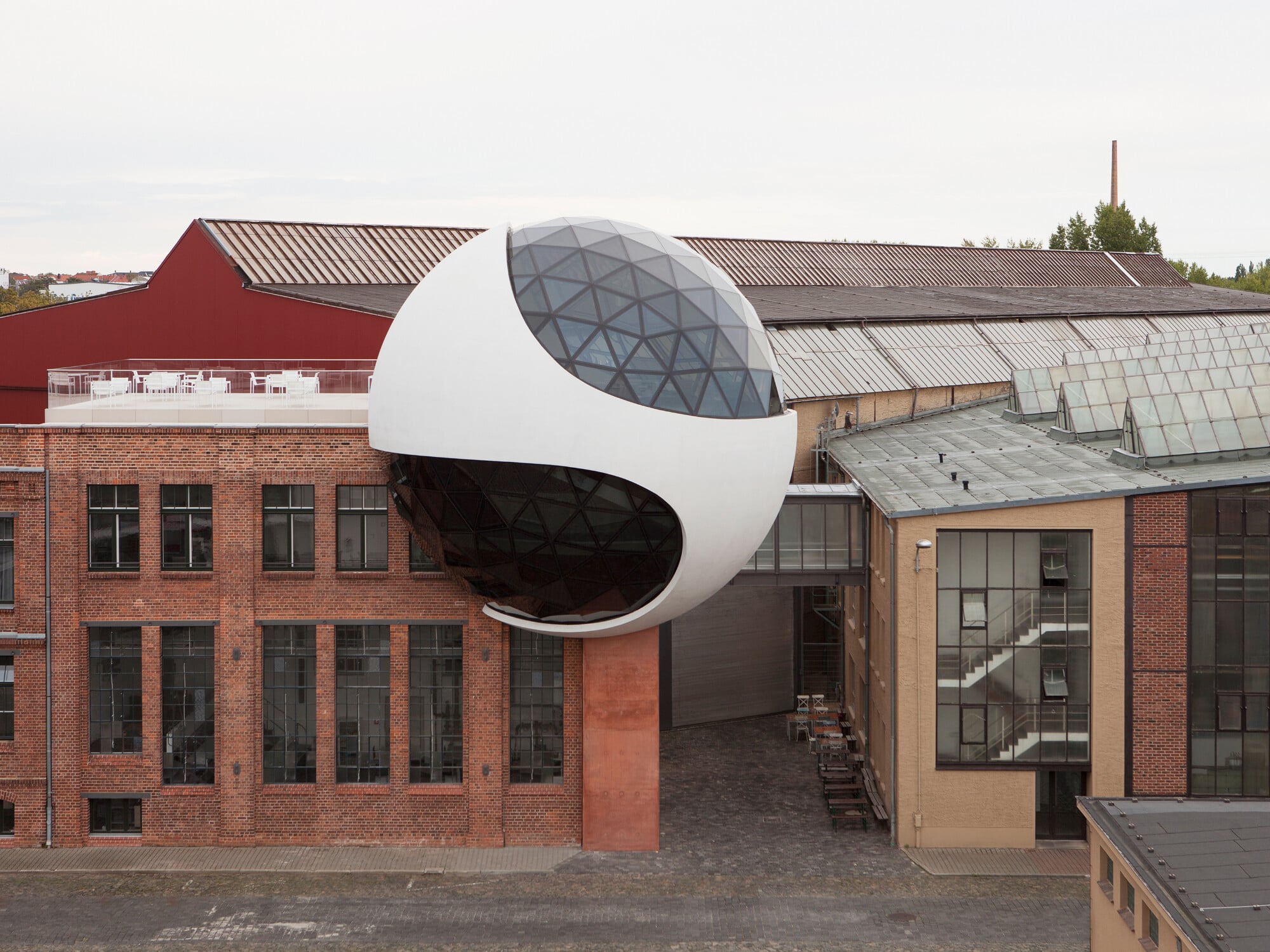 Auf dem Werksareal der Unternehmen Heiterblick und Kirow in Leipzig erweitert die Niemeyer Sphere eine Betriebskantine in einem bestehenden Ziegelbau von 1927.