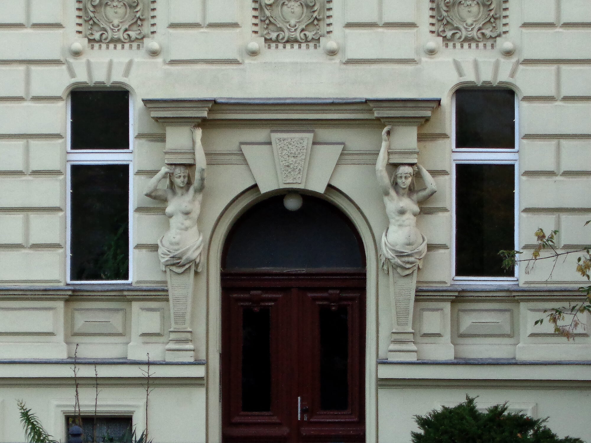 Ein Paar Hermen trägt einen Ziergiebel oberhalb einer Eingangstür