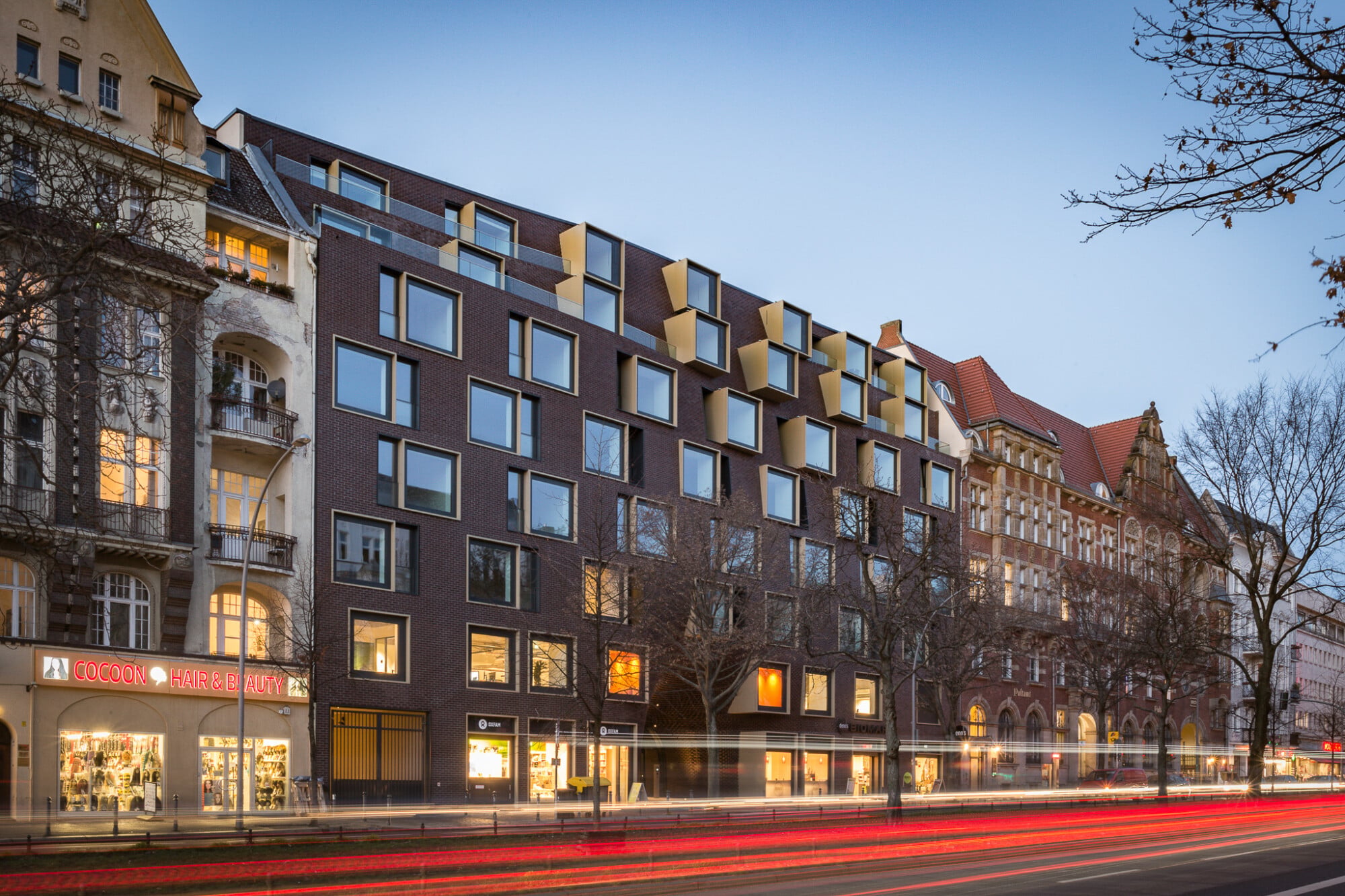 Die straßenseitige Außenwand erscheint im Eingangsbereich und in den oberen Geschossen als sei sie „eingedrückt“.
