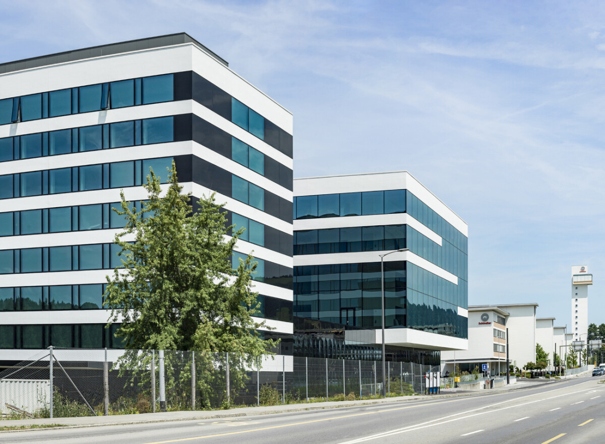 Südansicht von der Straße: Das achtgeschossige Bürogebäude (vorne im Bild) ist durch die Fassadengestaltung optisch mit dem Neubau verknüpft. Die versetzten Ebenen des Ausstellungshauses sind ablesbar.
