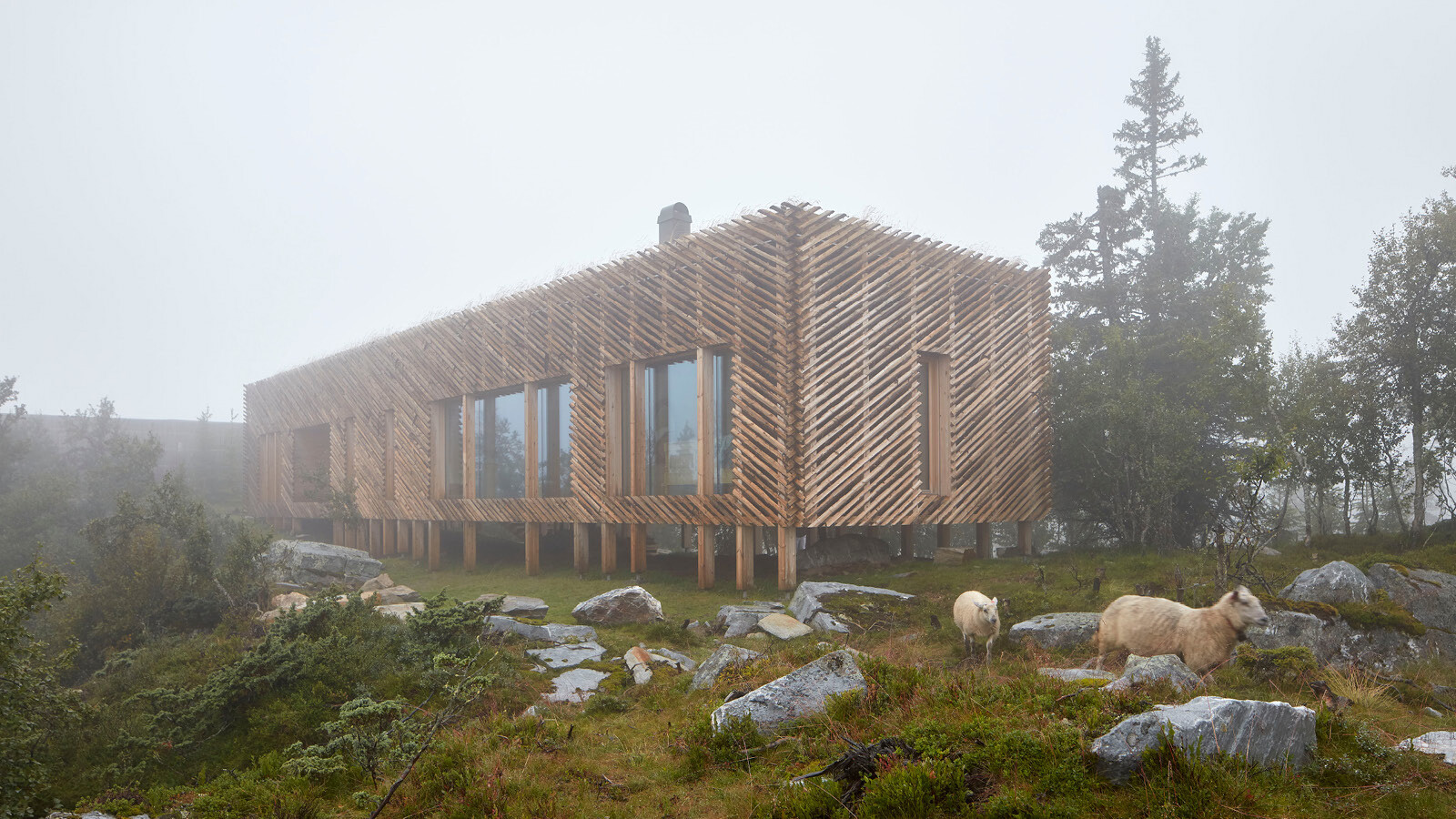 Mit einer Fassade aus unbehandelten, geviertelten Rundhölzern fügt sich der Gebäuderiegel harmonisch in die raue Landschaft.