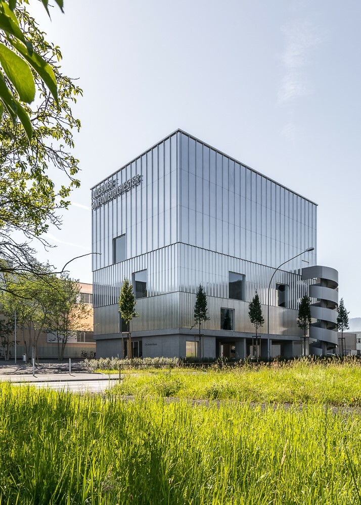 Die Breite der Aluminiumelemente, mit denen die obersten drei Geschosse des Kubus‘ verkleidet sind, variiert von feinen vertikalen Streifen im ersten Obergeschoss zu breiten Bahnen im dritten Obergeschoss.