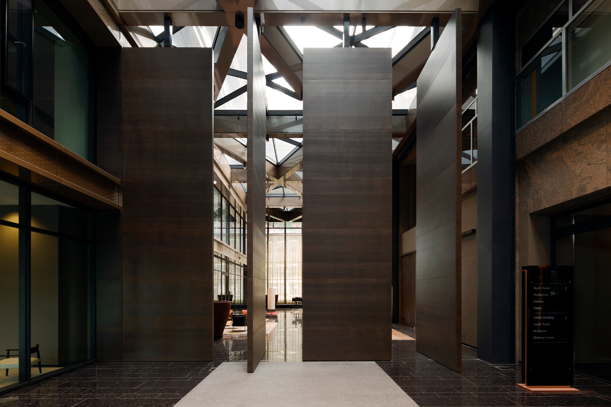 Pivot-Türen drehen um einen feststehenden Punkt, durch den eine senkrechte Rotationsachse verläuft.  (im Bild: Aluminium-Holz-Pivot-Tür in einem Atrium in Amsterdam, Öffnungsvariante).