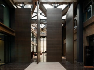 Pivot-Türen sind eine besondere Form der Drehtür. Die Bezeichnung leitet sich vom französischen Verb pivoter (= schwenken, schwingen) her (im Bild: geöffneter Zustand einer Aluminium-Holz-Pivot-Tür in einem Atrium in Amsterdam).