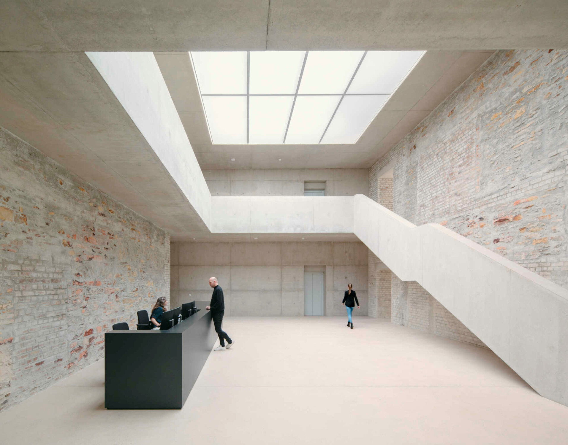 Im Foyer hinter der entkernten Kapelle harmonieren die historischen Mauerreste mit Sichtbeton und einer Tageslichtdecke.