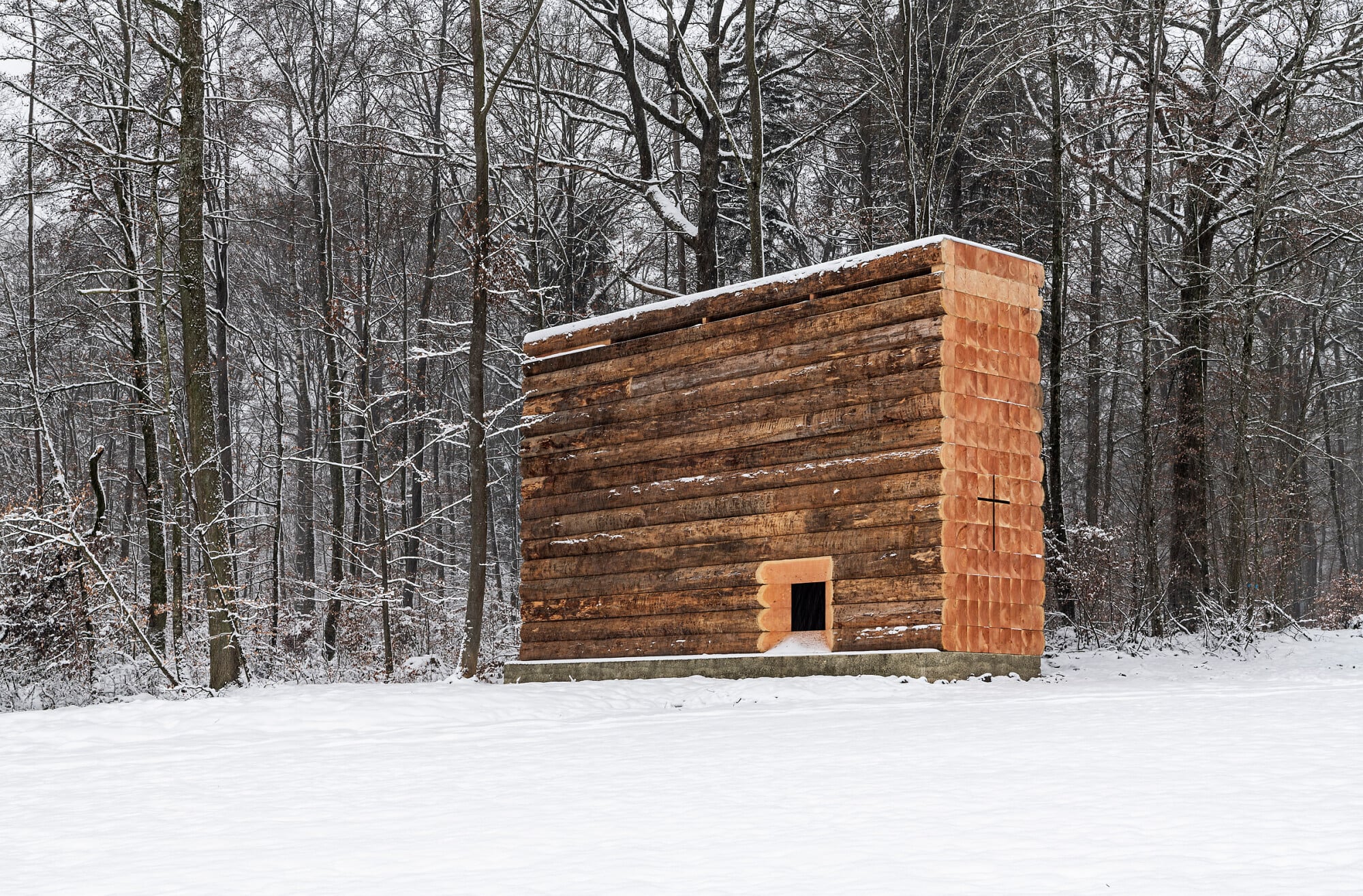 Beim Näherkommen wird das schmale Blockhaus erkennbar.