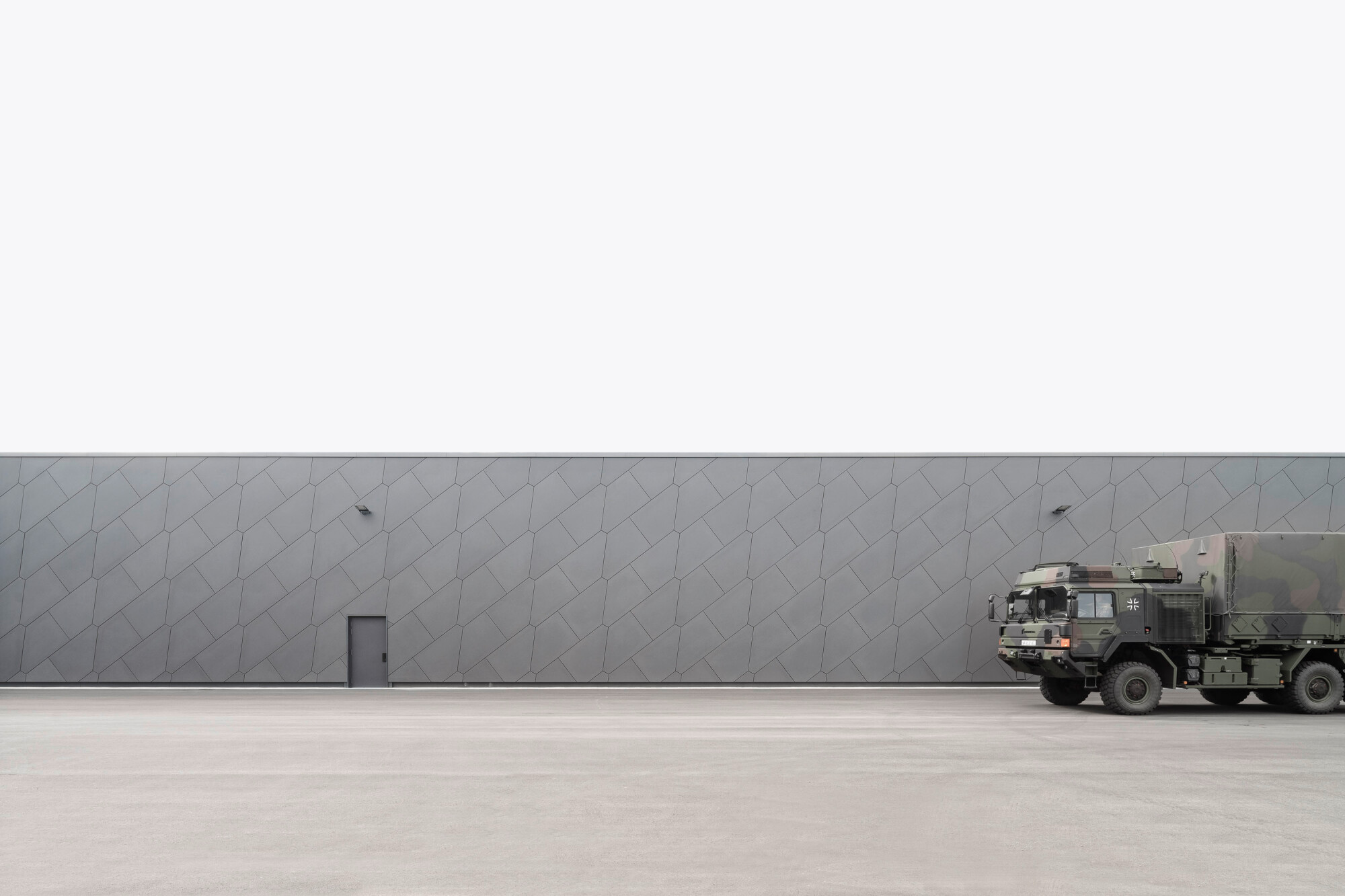 Die Halle, Nachschublager des Hubschaubers NH90, erhielt eine vorgehängte hinterlüftete Fassade aus grauen Faserzementplatten.