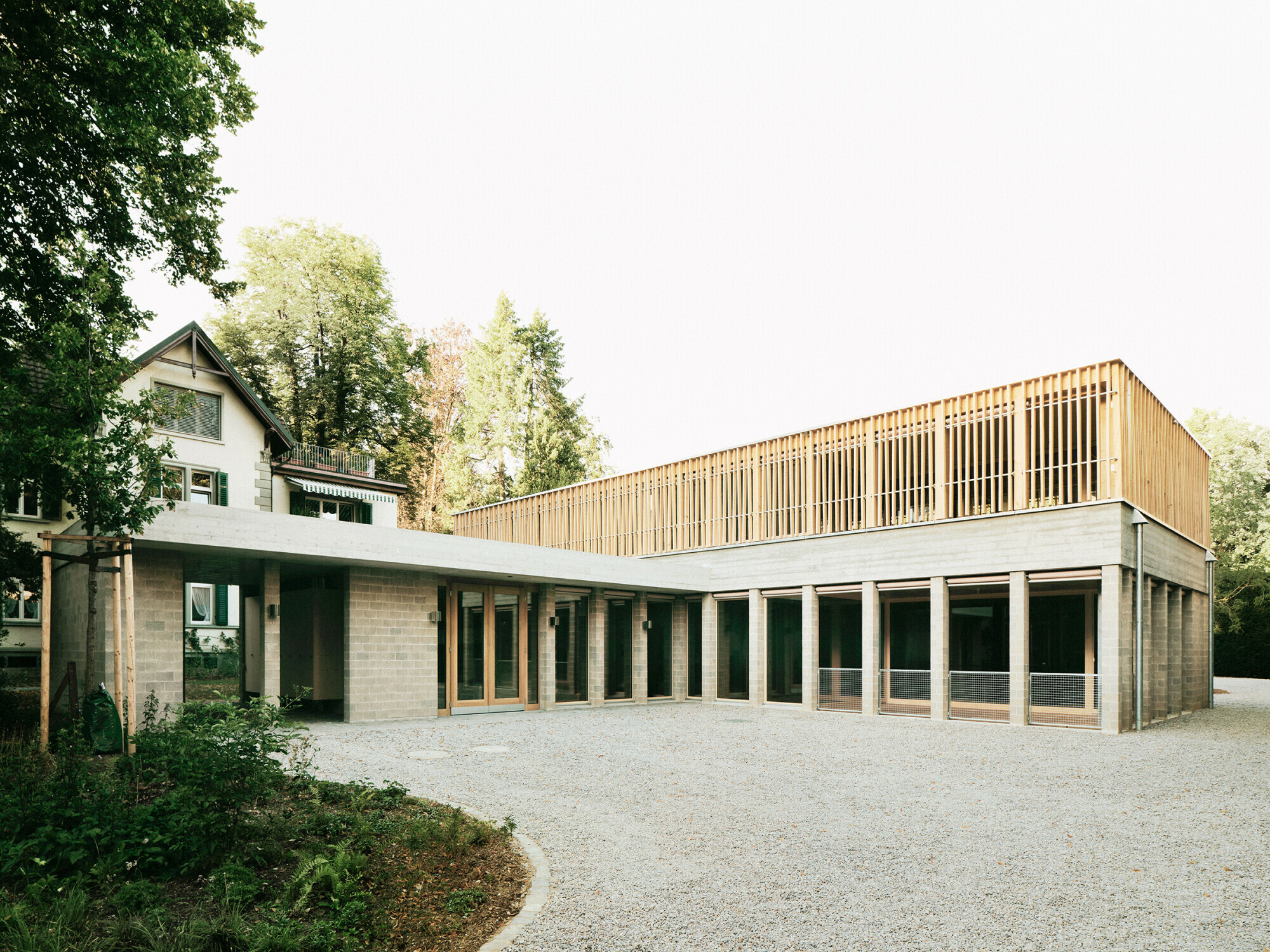 Durch den kreuzförmigen Grundriss wirkt das Gebäude kleiner und passt sich so in die Situation zwischen den historischen Prachtvillen ein, ohne in Konkurrenz zu diesen zu treten.