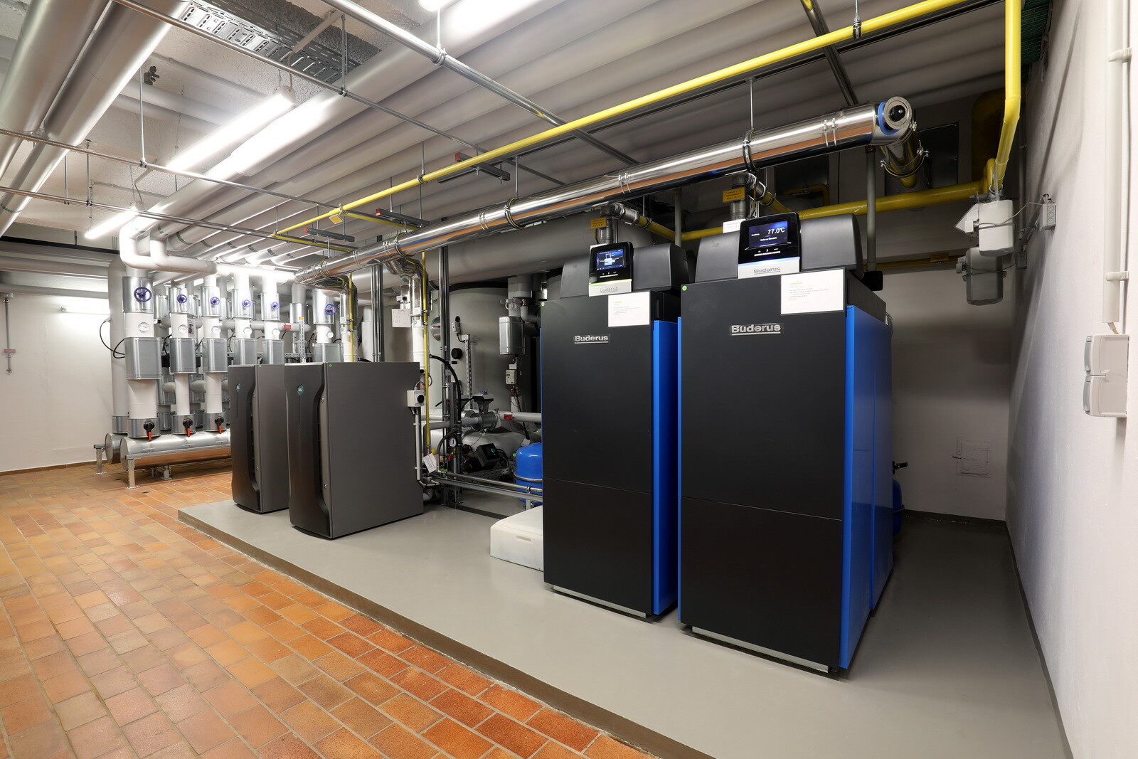 Die beiden Gas-Brennwertkessel Logano plus KB372 mit einer Gesamtheizleistung von 600 kW übernehmen die Spitzenlastabdeckung (vorne rechts im Bild). Ergänzt wird das Heizsystem durch zwei Brennstoffzellen BlueGEN BG-15 (hinten links).