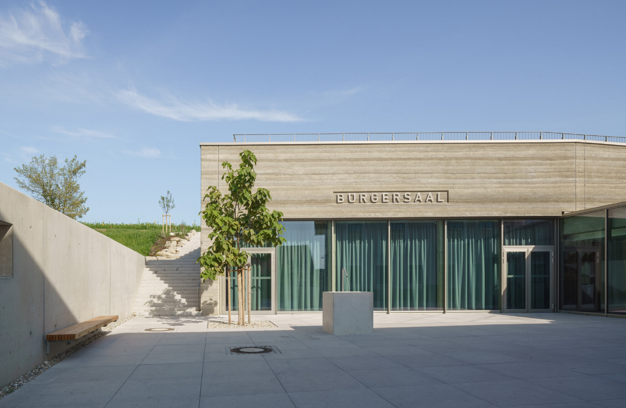 Während sich das Wirtshaus mit einer neuen Luftkalkputzfassade präsentiert, hüllt sich der Gemeindesaal oberirdisch in Stampfbeton. 