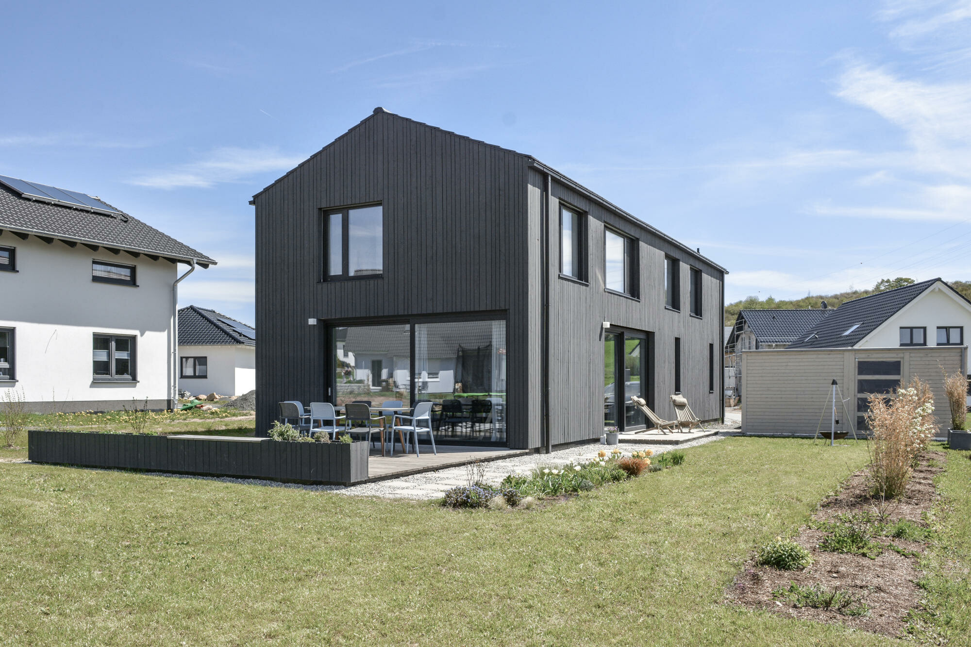 An zwei Seiten des Wohnraums gibt es große Schiebeelemente und Terrassen (Ansicht West).