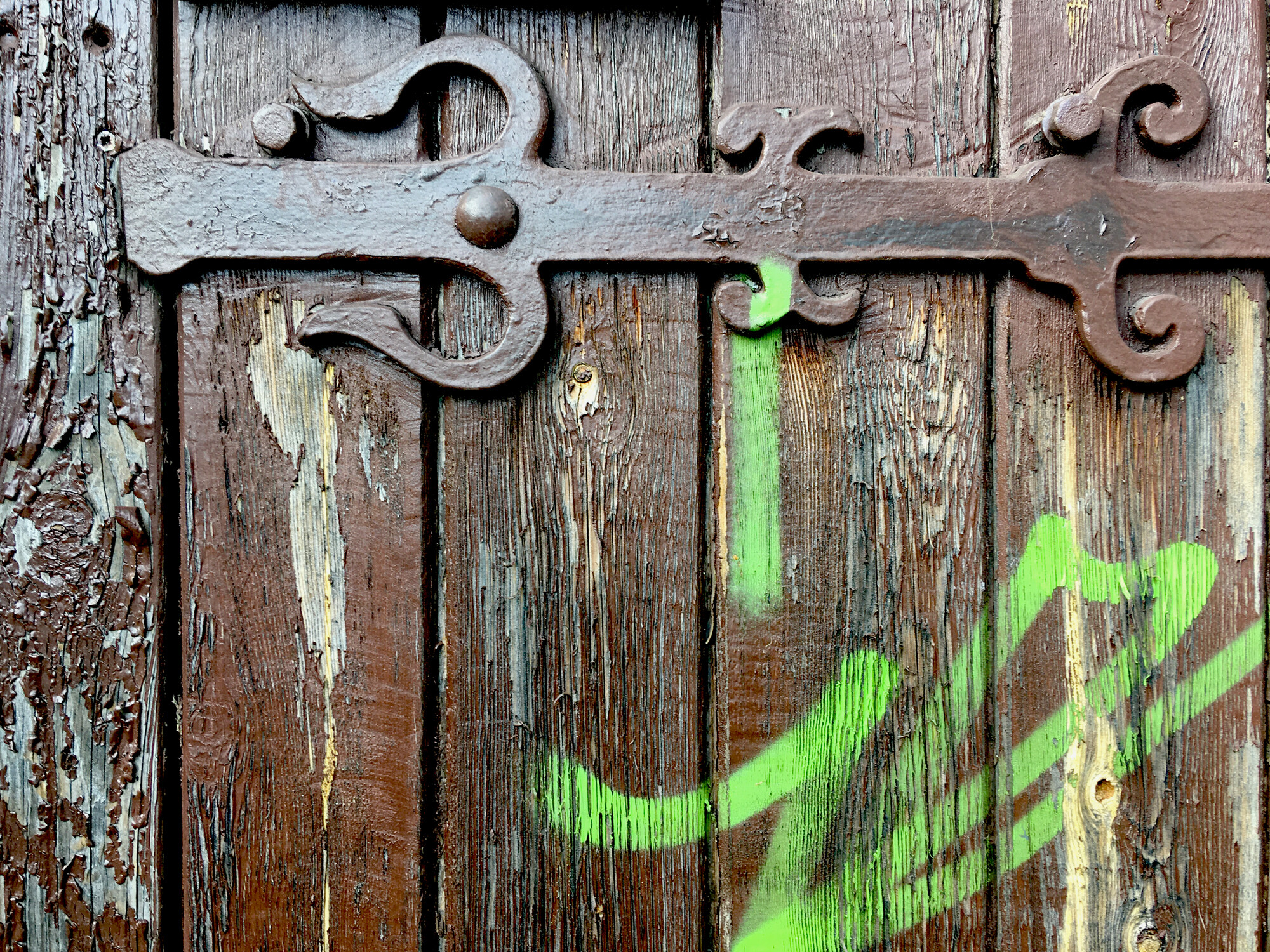 Detail einer Holztür mit abgeplatzter Lackschicht und sichtbaren Rissen