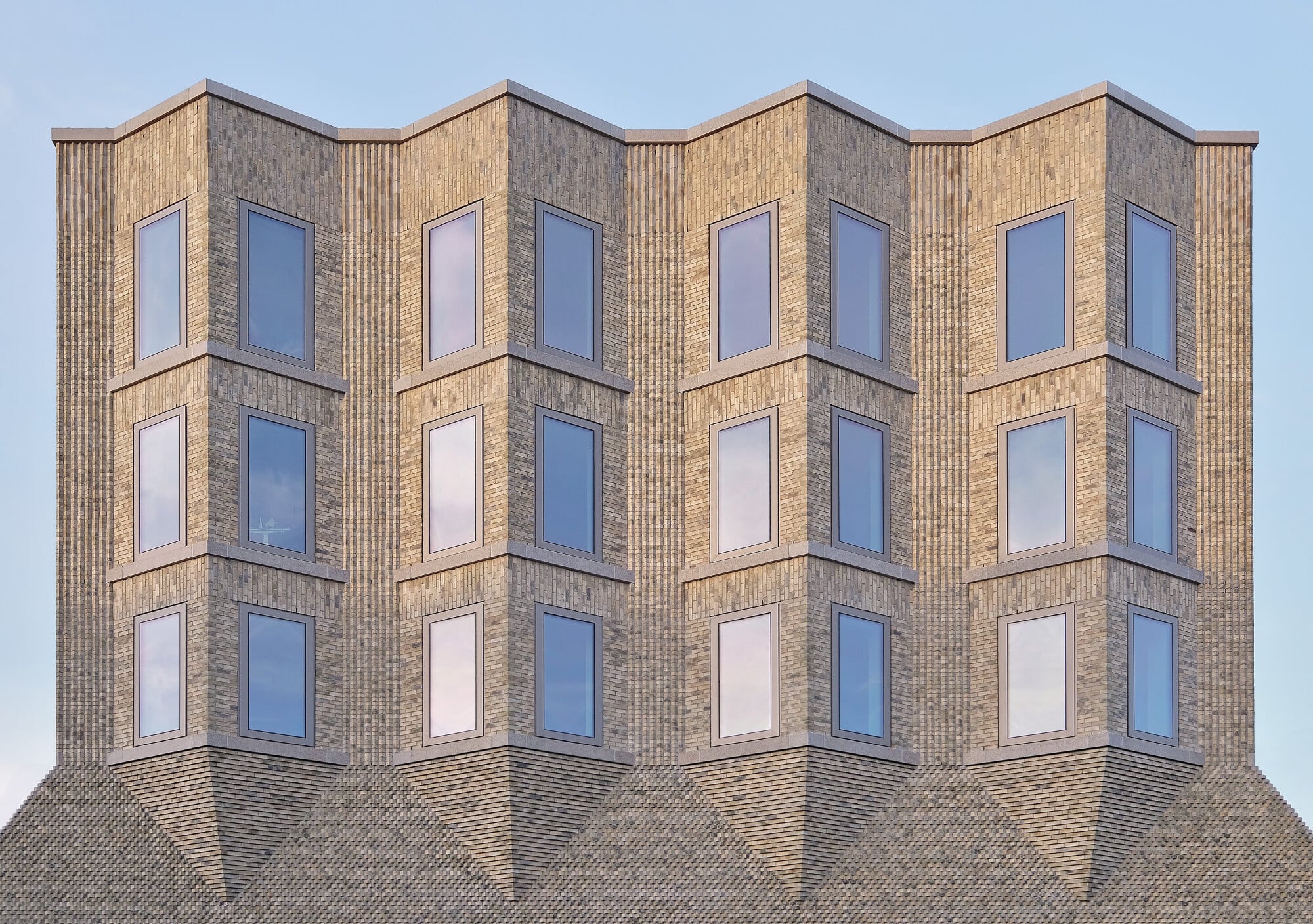 Mit seiner hoch aufragenden, hellen Backsteinfassade, aus der sich straßenseitig vier spitze Erker entfalten ist der Neubau der Protagonist des Projektes. 
