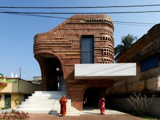 Mit rund fließenden Ecken, bogenförmigen, großen Öffnungen und einer ornamentalen Mauerwerksfassade hebt sich das Gallery House Community Center nach Plänen von Abin Design Studio deutlich von seiner Umgebung ab.